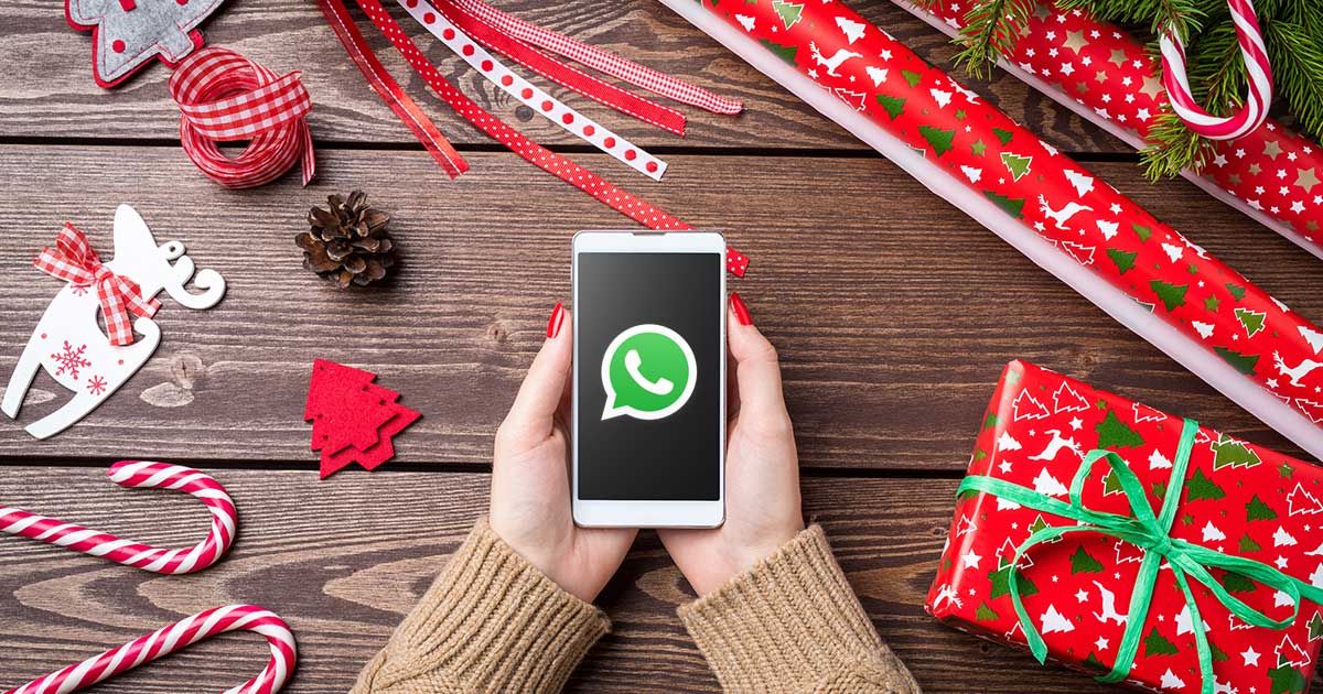 WhatsApp-Weihnachtsgrüße: Handy mit WhatsApp-Logog über einem Weihnachtstisch