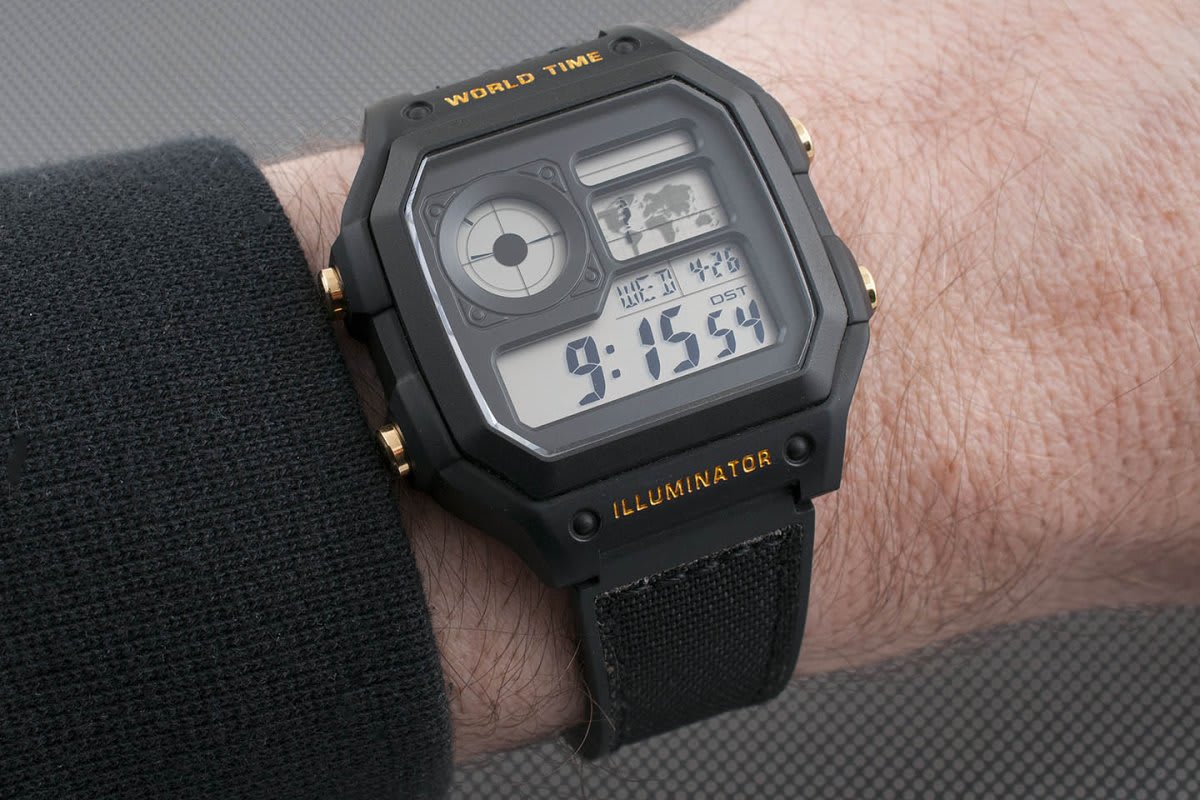 Close-up of a Casio AE-1200 Royale digital watch showing world time, date, and other features on a black strap