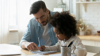 A male tutor explaining a topic to a young student for an in-person lesson.