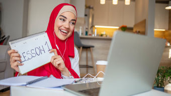A tutor holding a cue card for a tutor she is teaching online.
