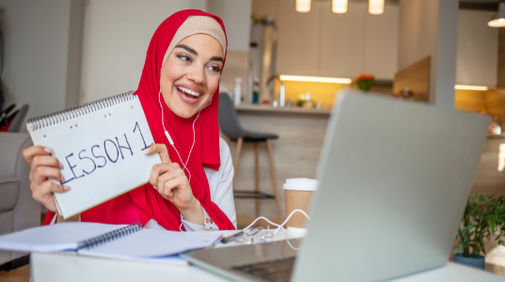A tutor holding a cue card for a tutor she is teaching online.