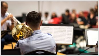 A trombone player performing music as part of an orchestra.
