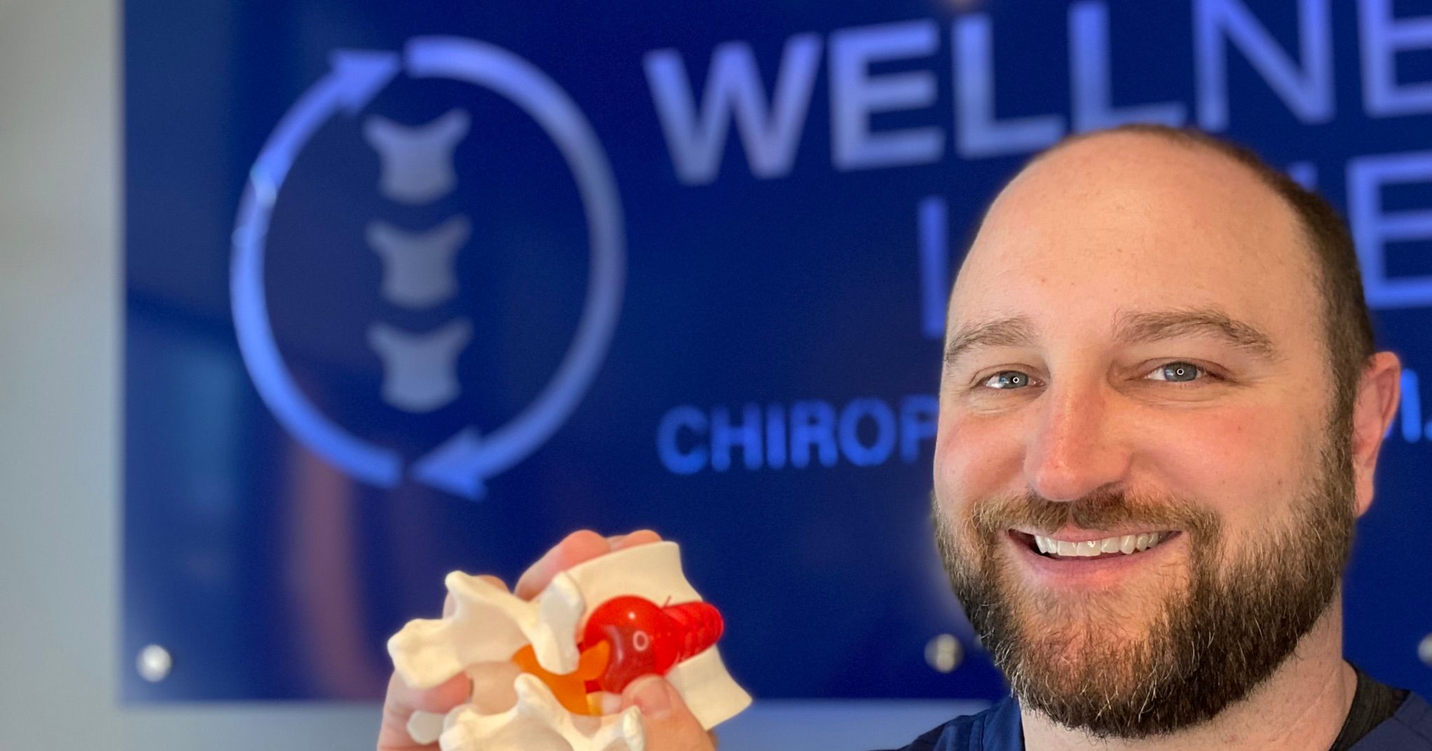 Dr Brent Smarinsky DC of Wellness Lane Chiropractic Farmers Branch holding a herniated disc model