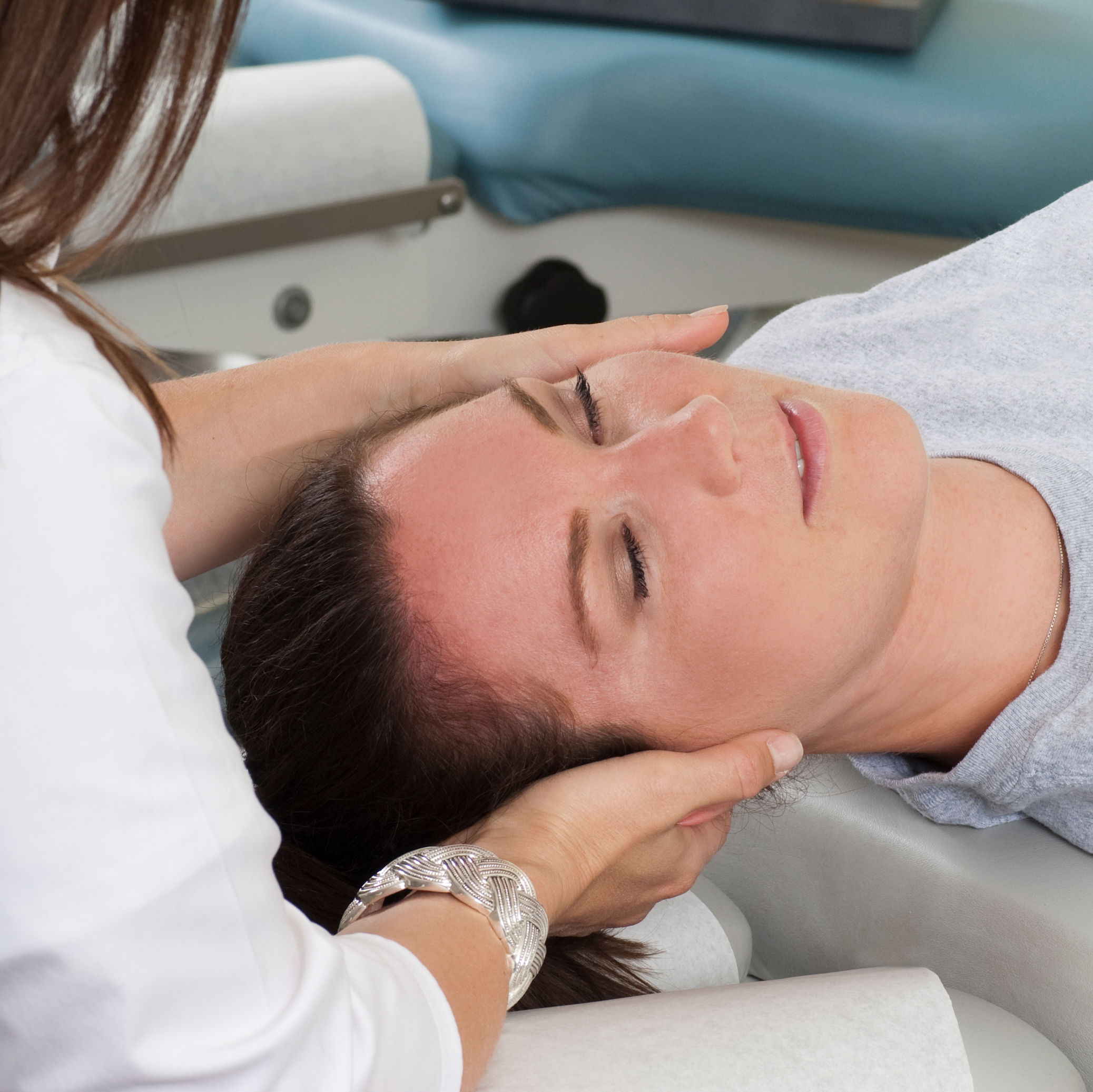 Woman lying on table while chiropractor massages n