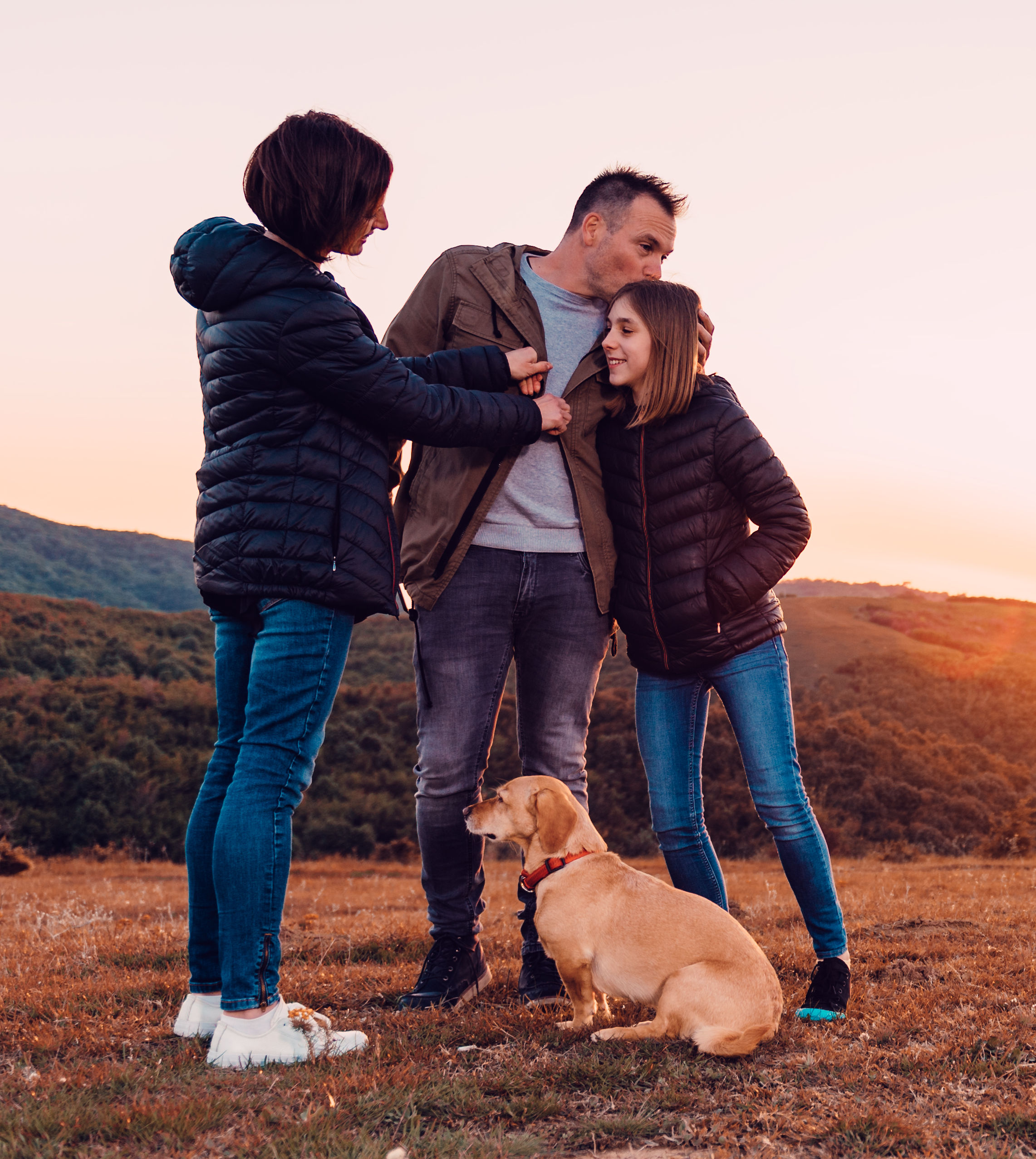 Family with dog embracing while standing on the hi
