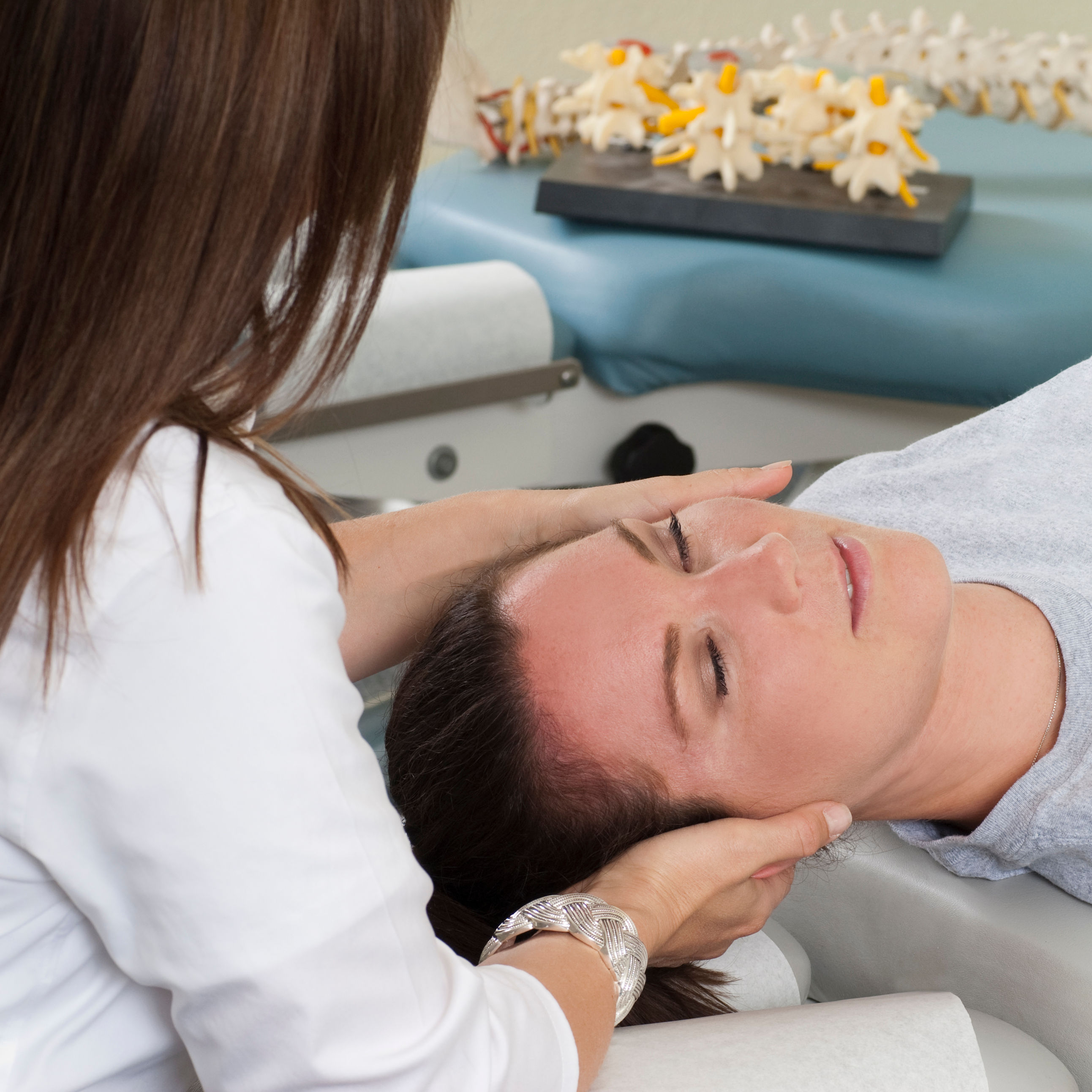 Woman lying on table while chiropractor massages n