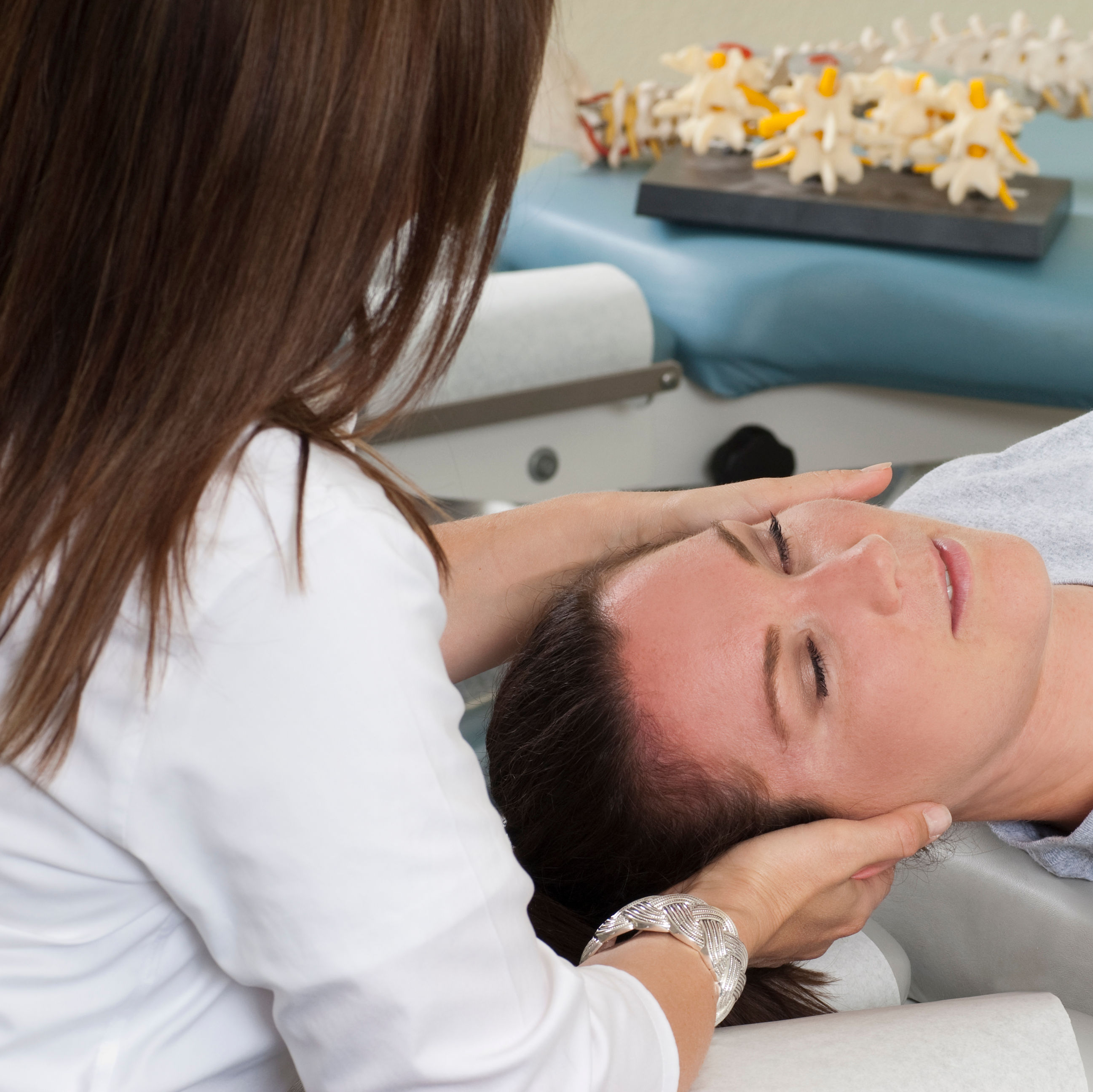 Woman lying on table while chiropractor massages n