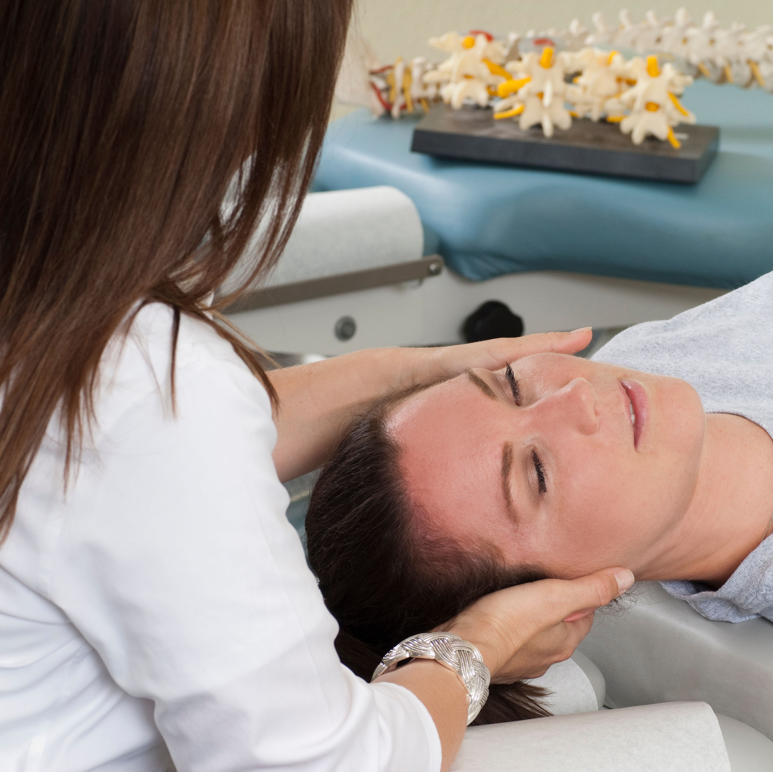 Woman lying on table while chiropractor massages n