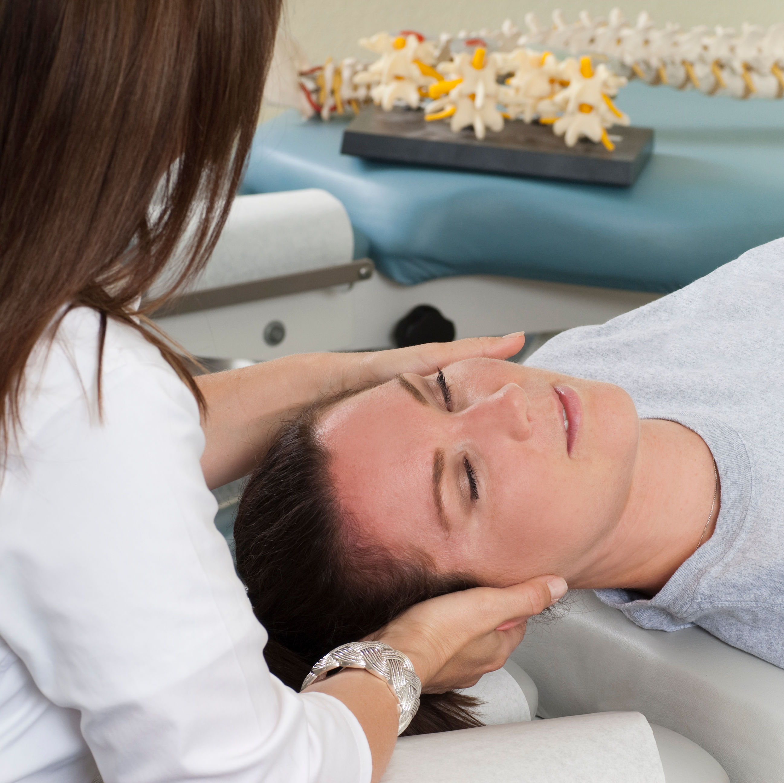 Woman lying on table while chiropractor massages n