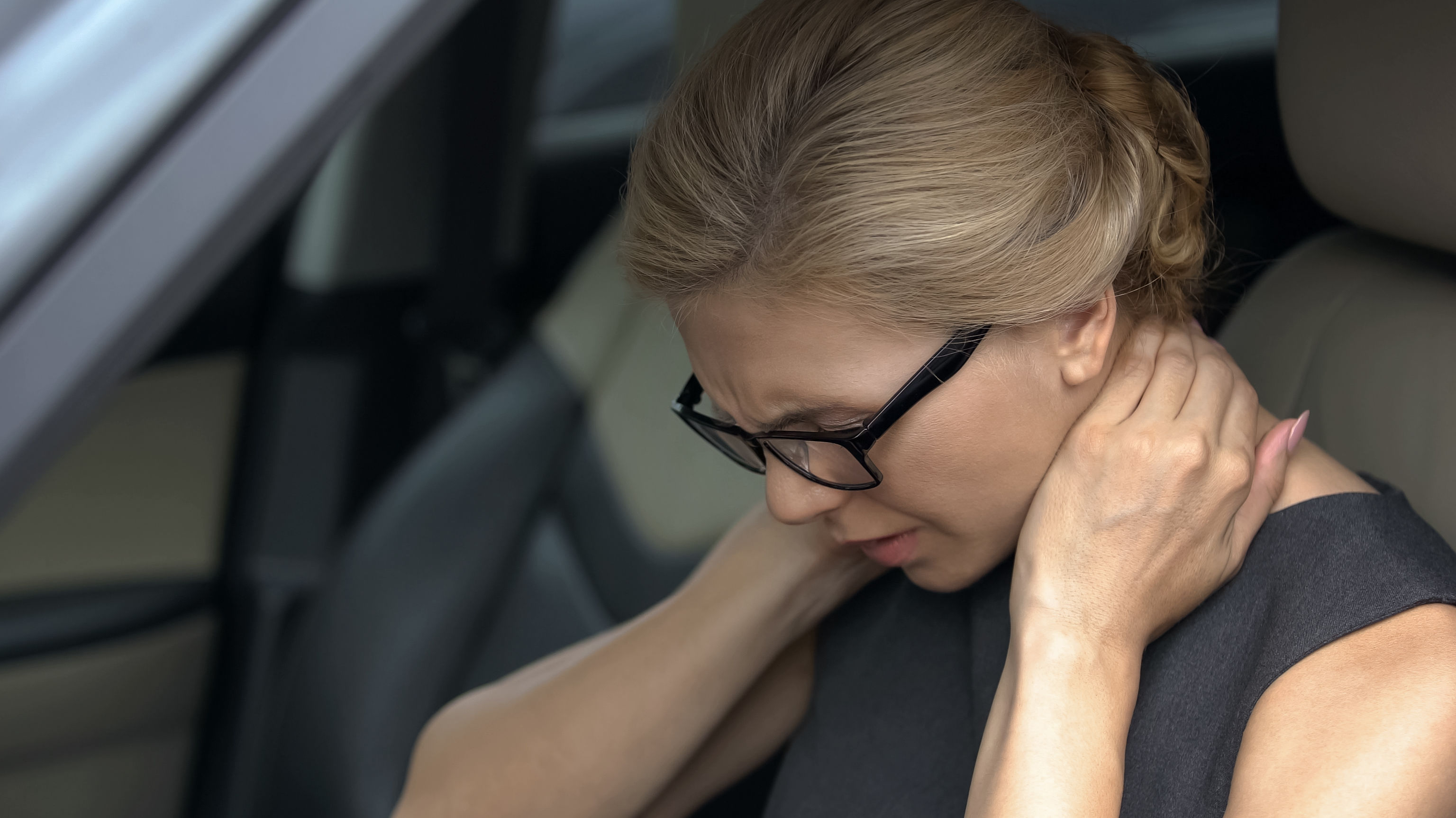Exhausted woman feeling neck pain, sitting in auto