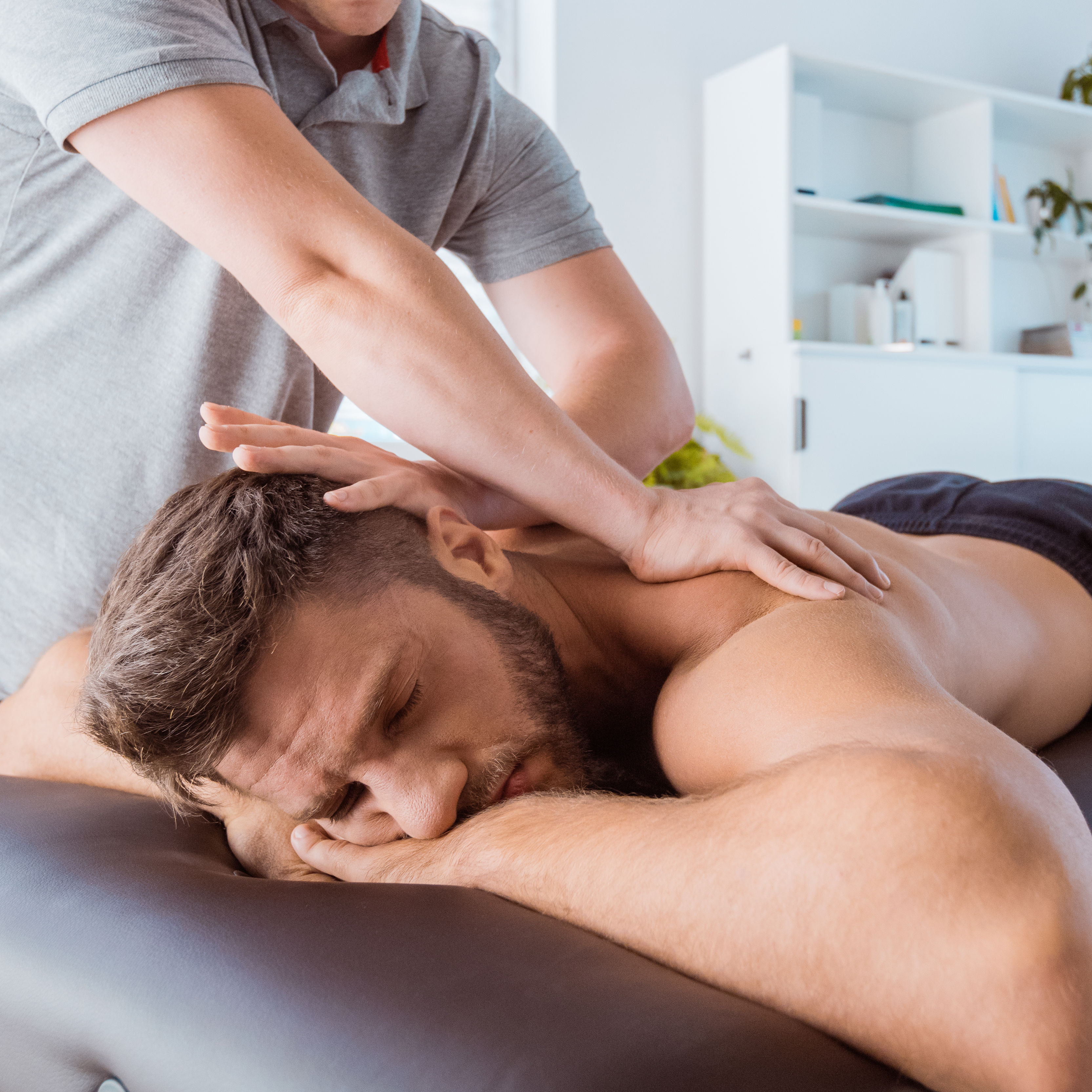Massage therapist massaging back of the young man