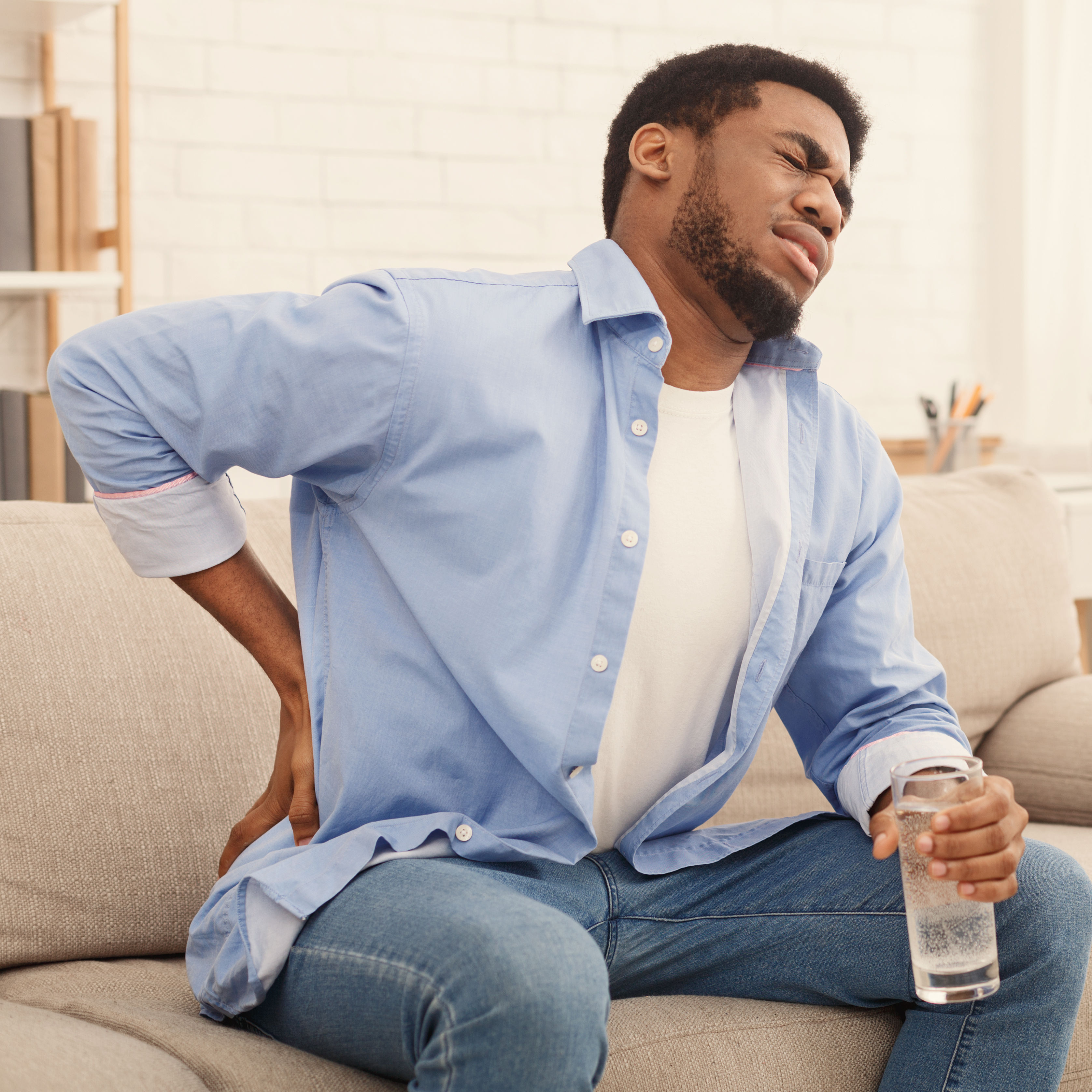 Young black man with back pain at home