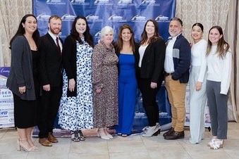 award winning woman in a group photo with 8 other people