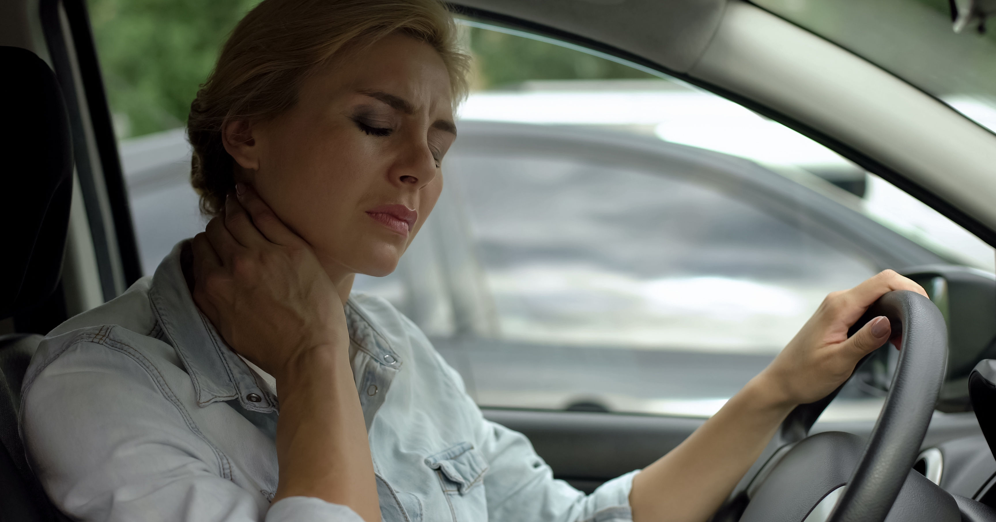 Tired female driver sitting in auto and massaging 