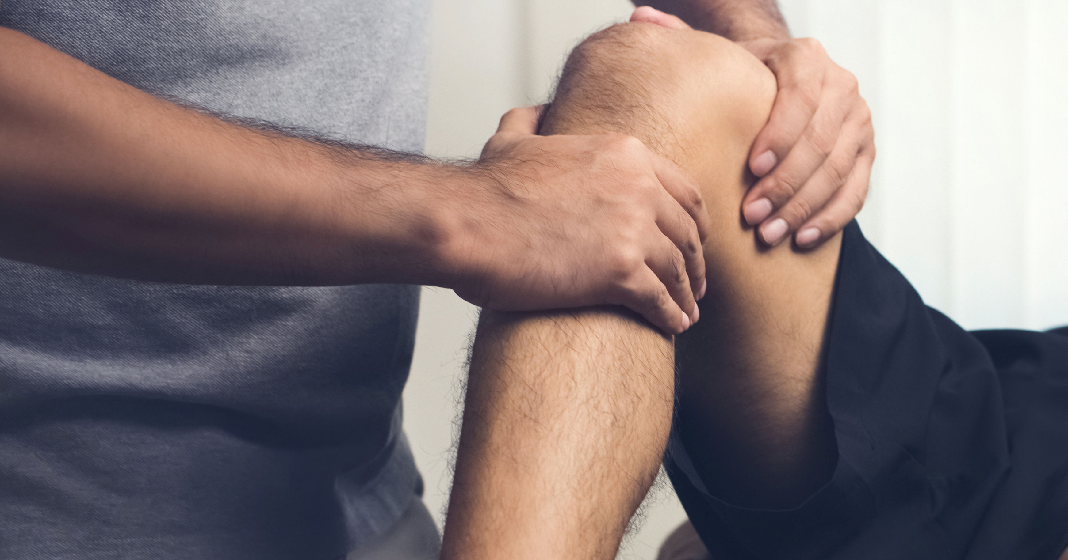 Therapist treating injured knee of athlete male pa