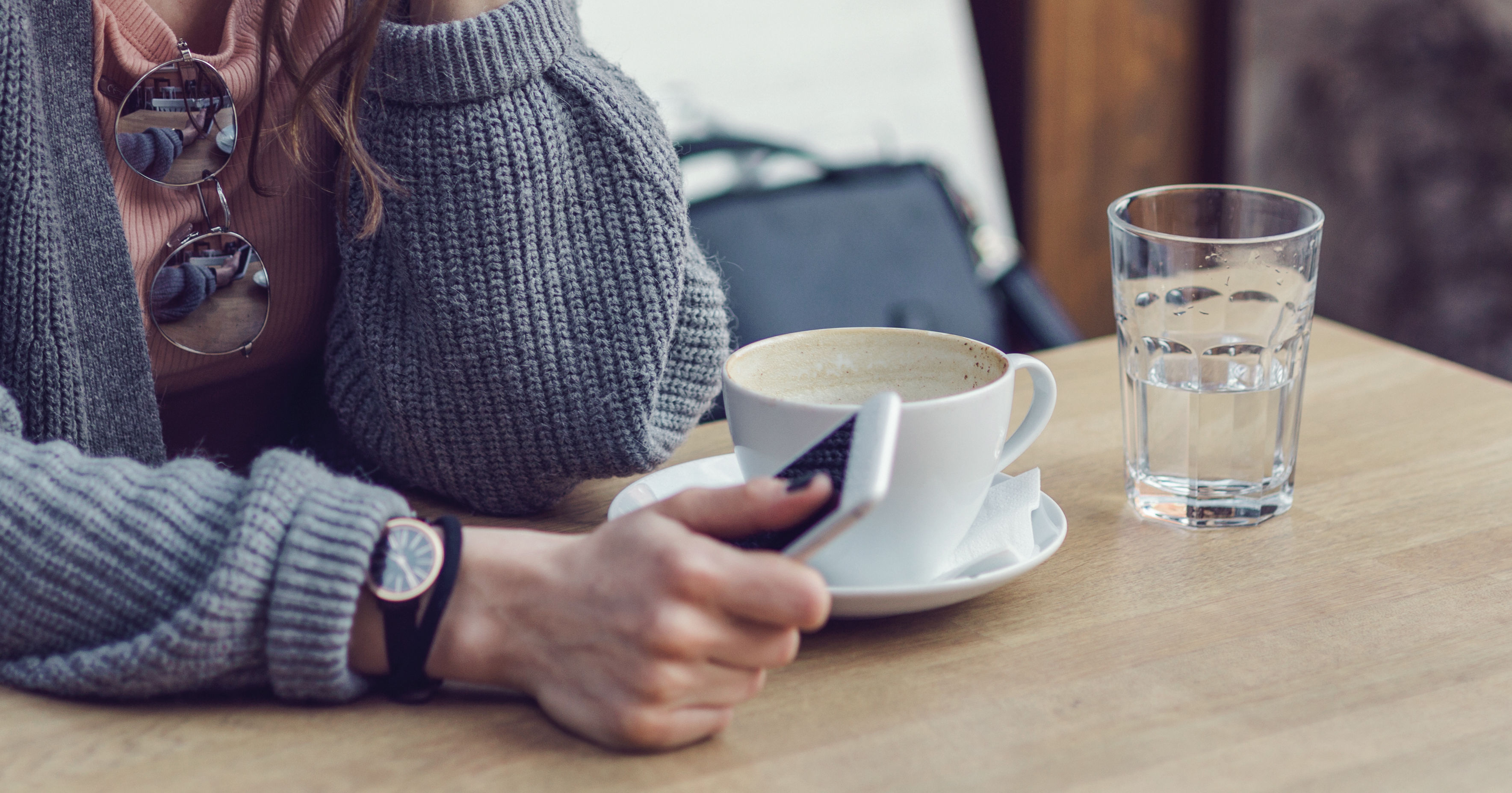 Woman sitting alone, having coffee and texting on