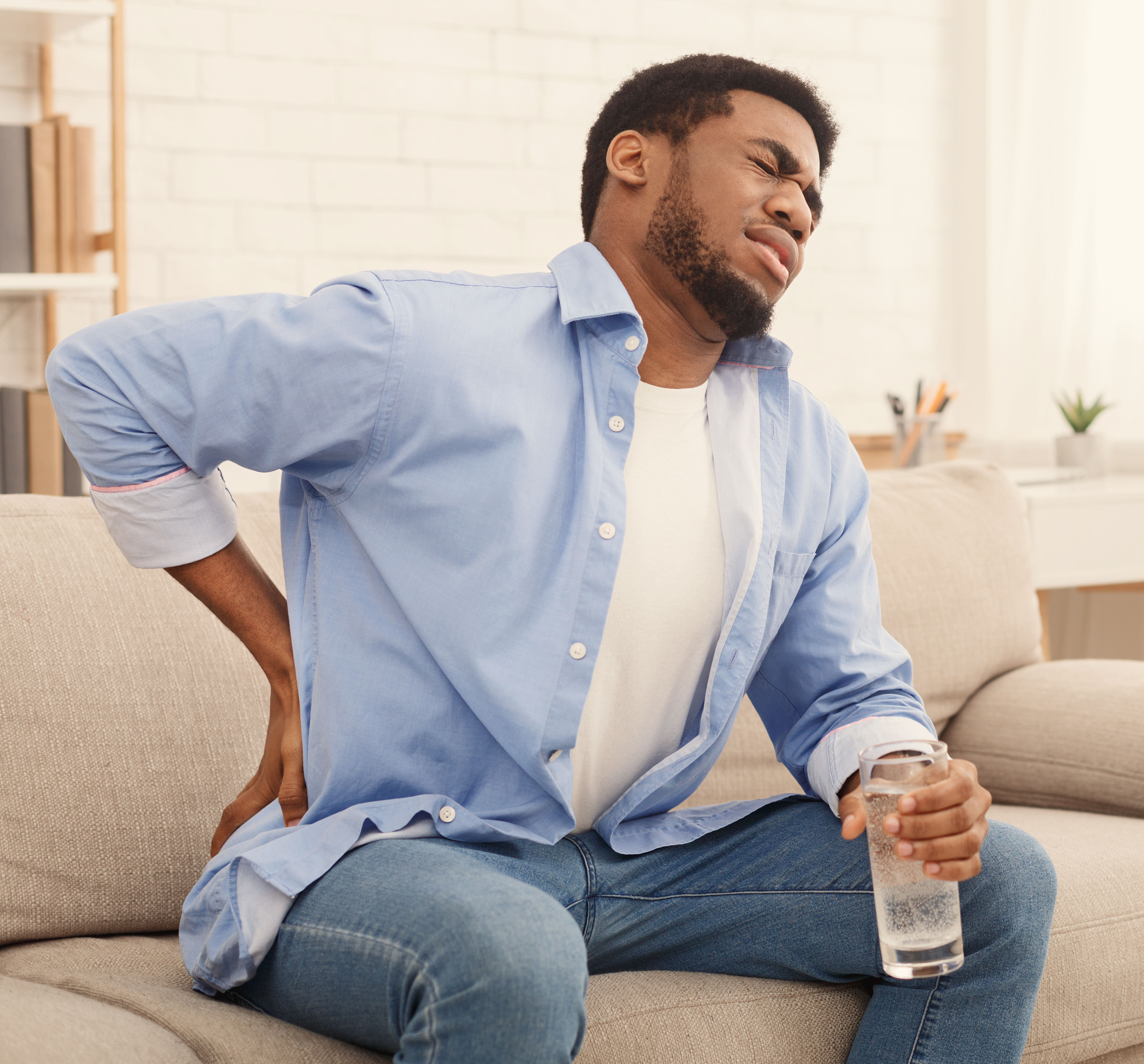 Young black man with back pain at home