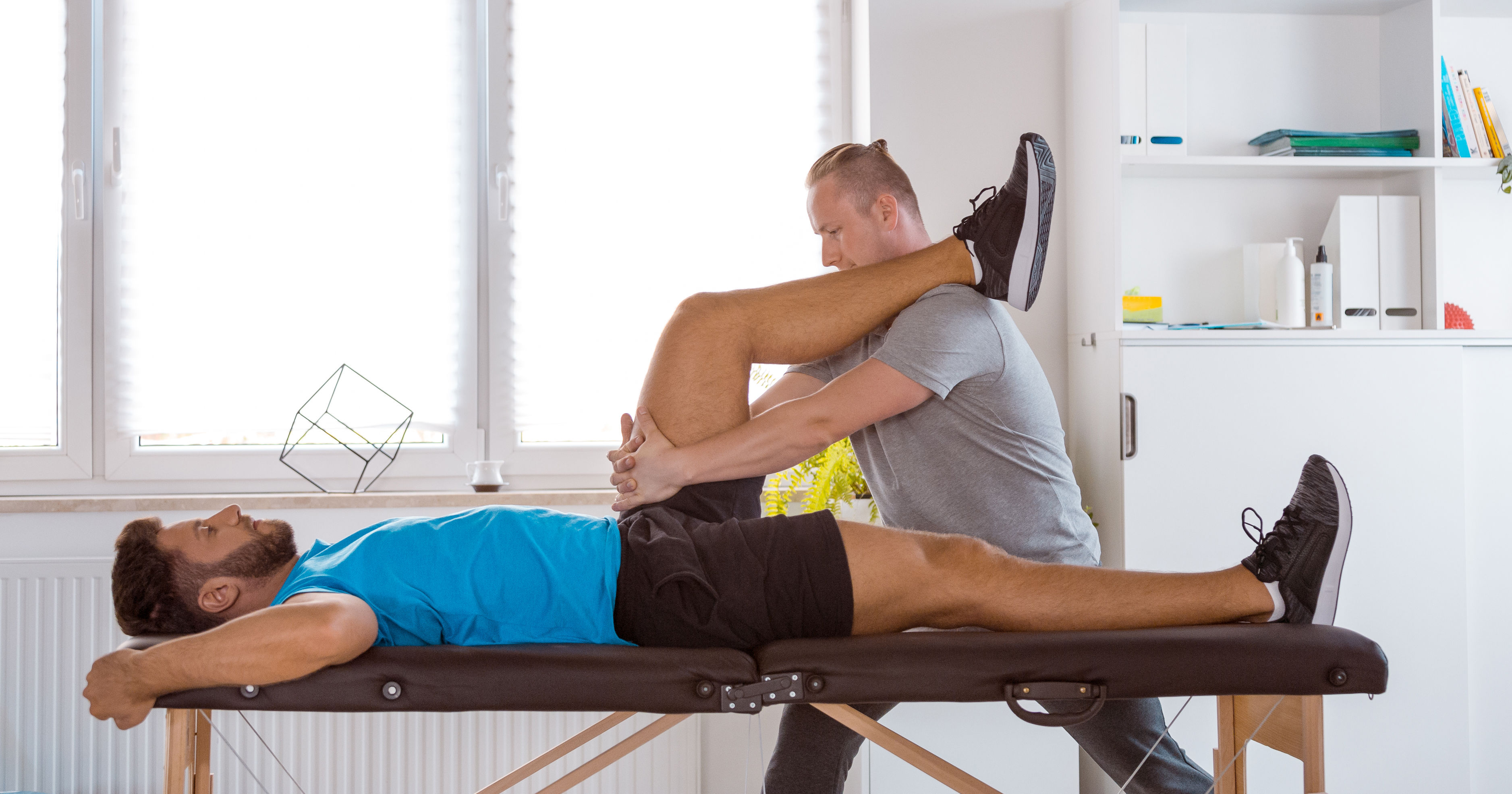 Physical therapist examining young man in rehabili