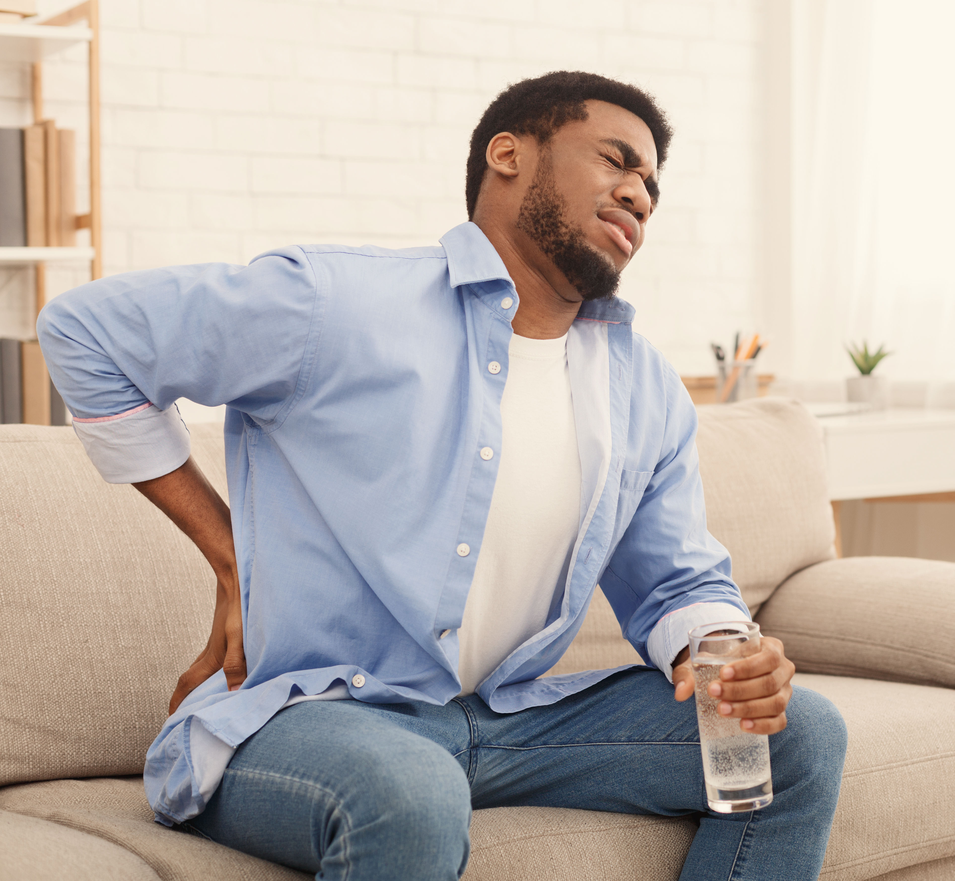 Young black man with back pain at home