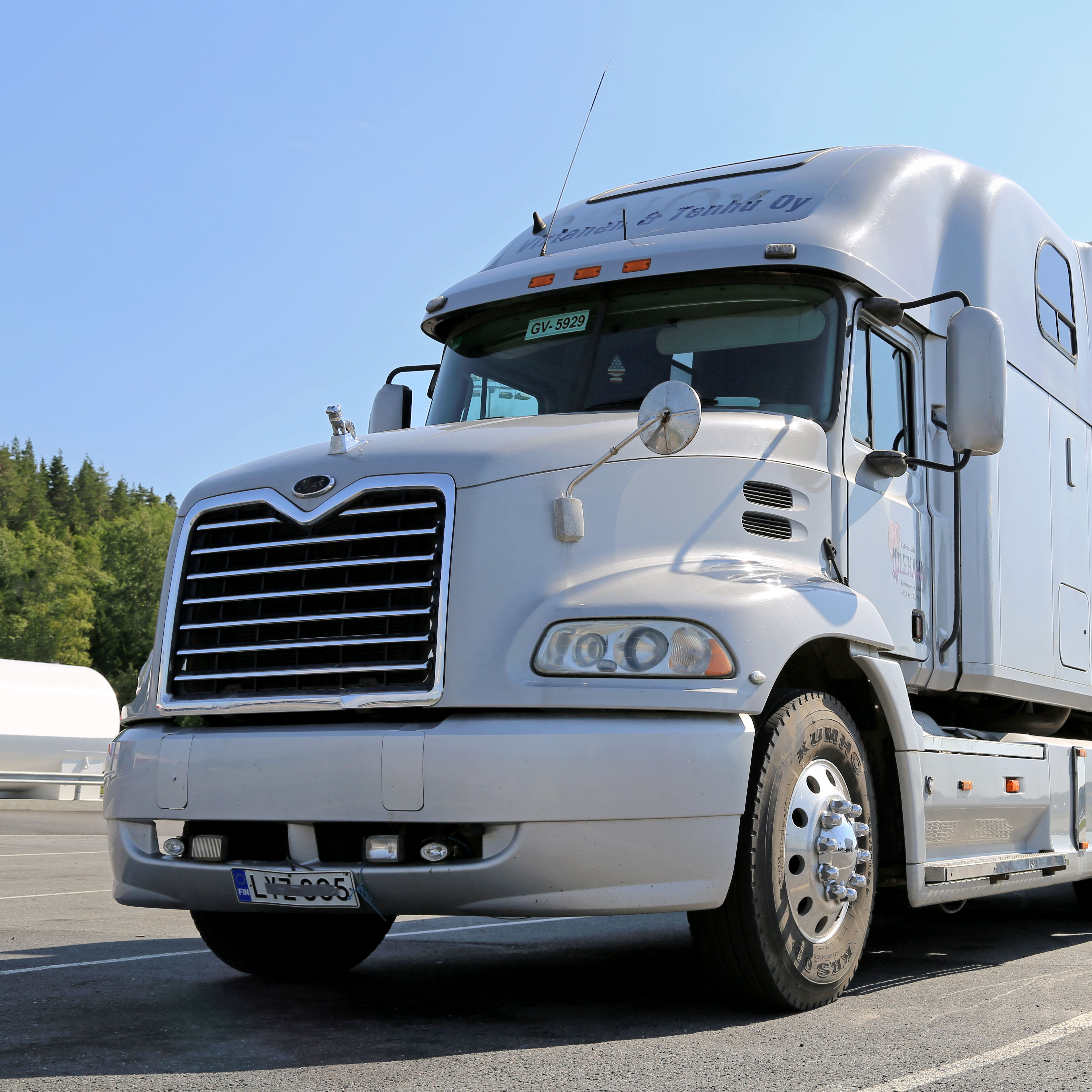 up close light grey mack 16 wheeler truck on highway blue sky