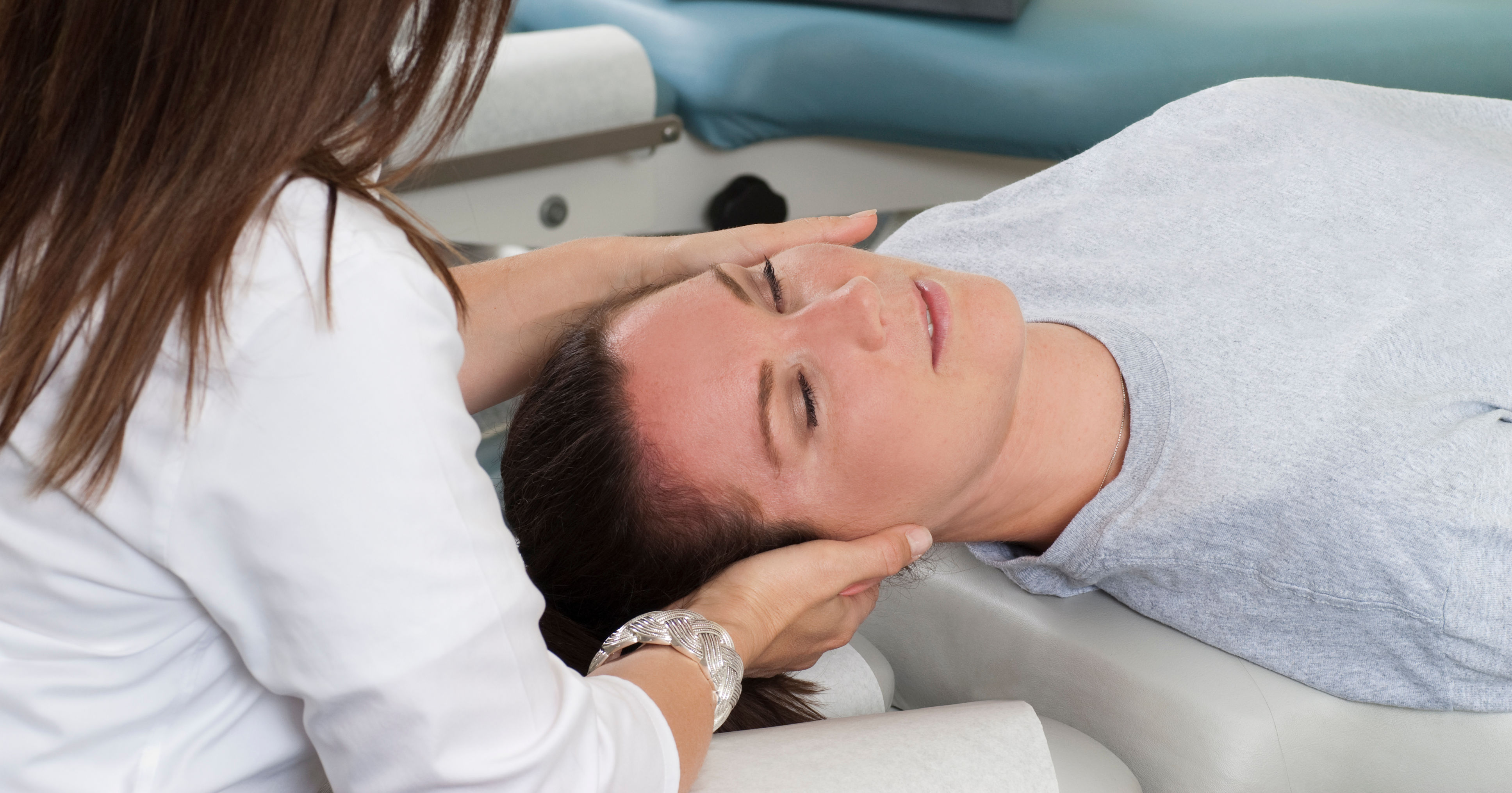 Woman lying on table while chiropractor massages n