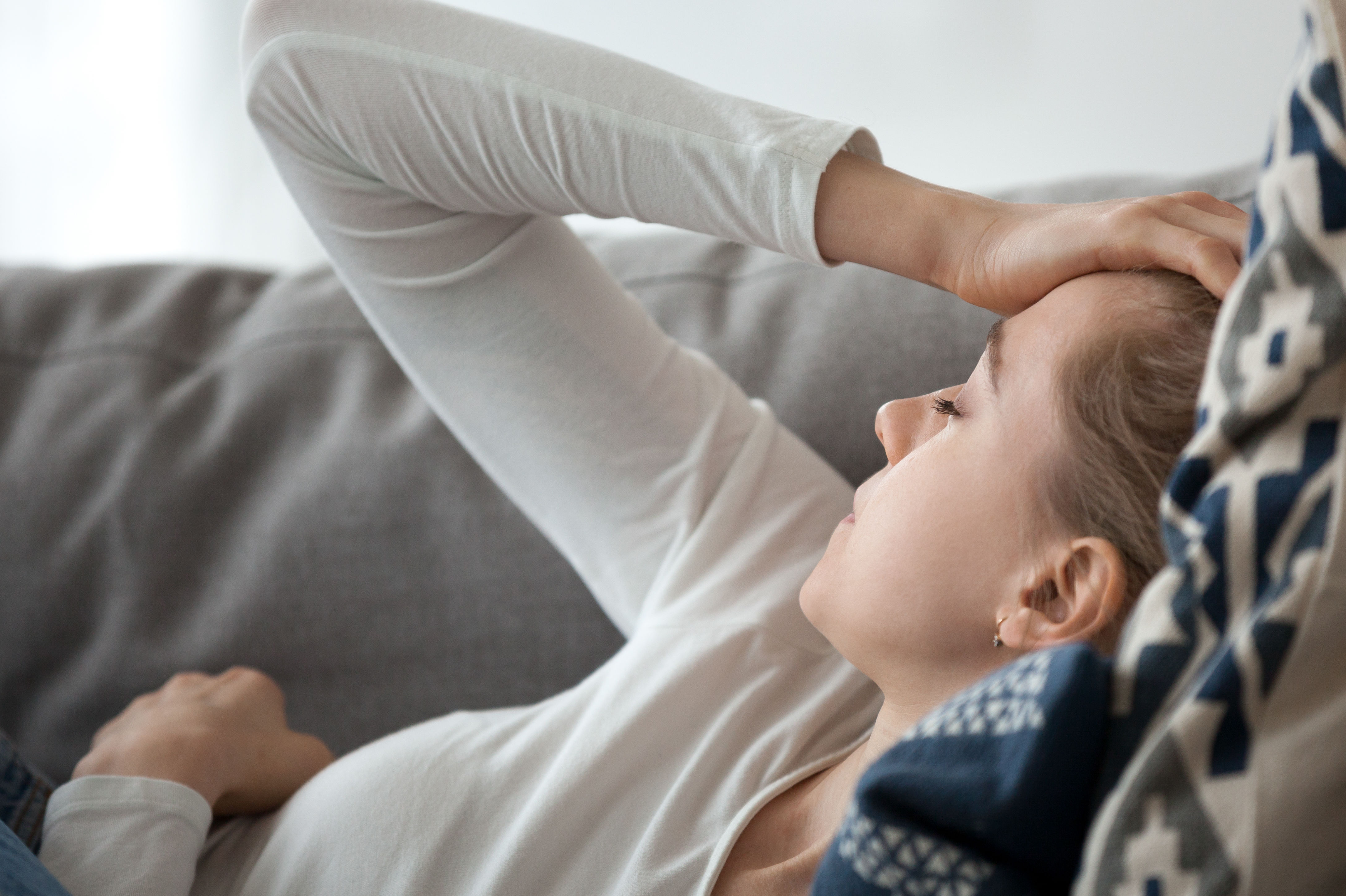 Upset depressed young woman lying on couch feeling
