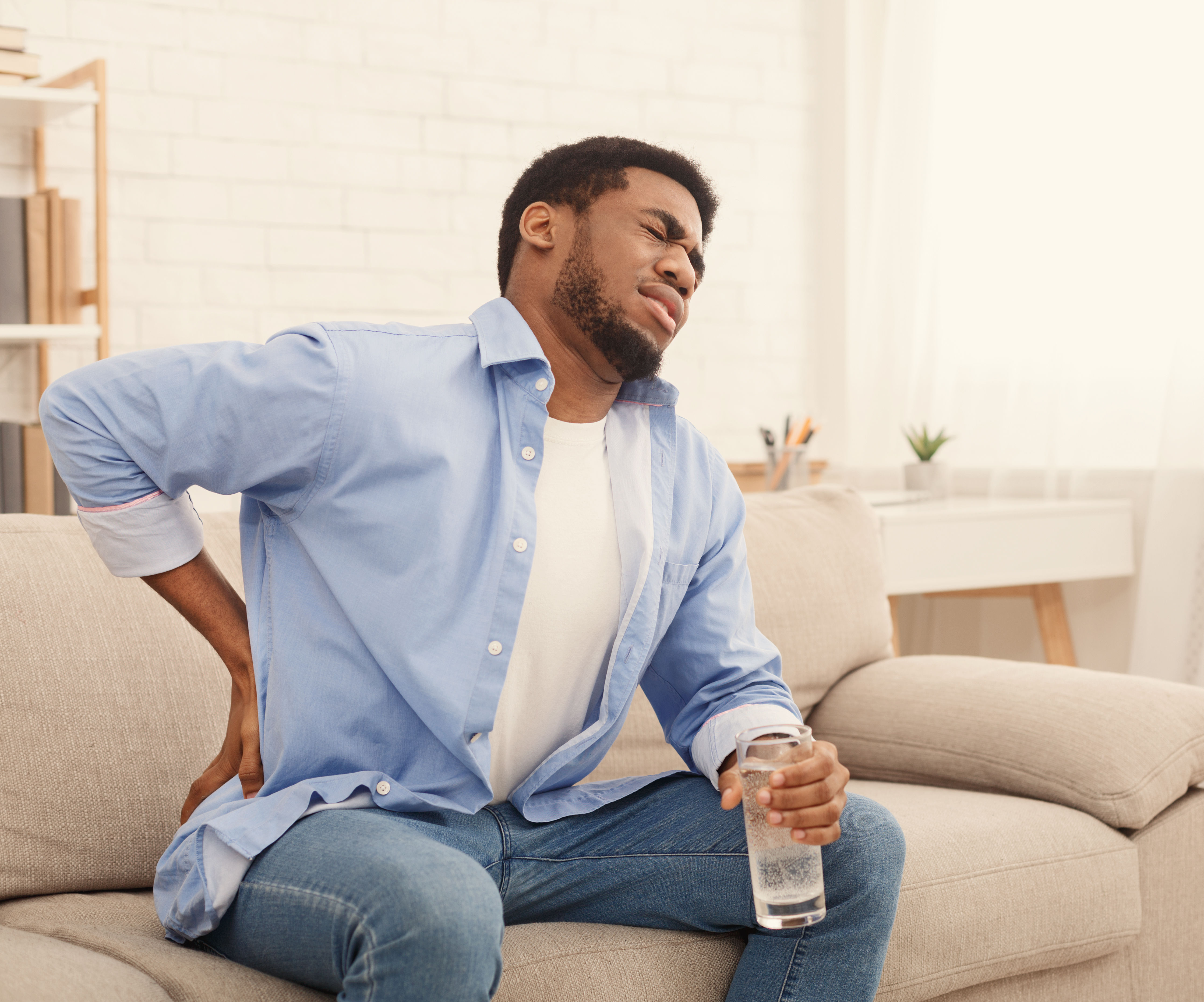 Young black man with back pain at home