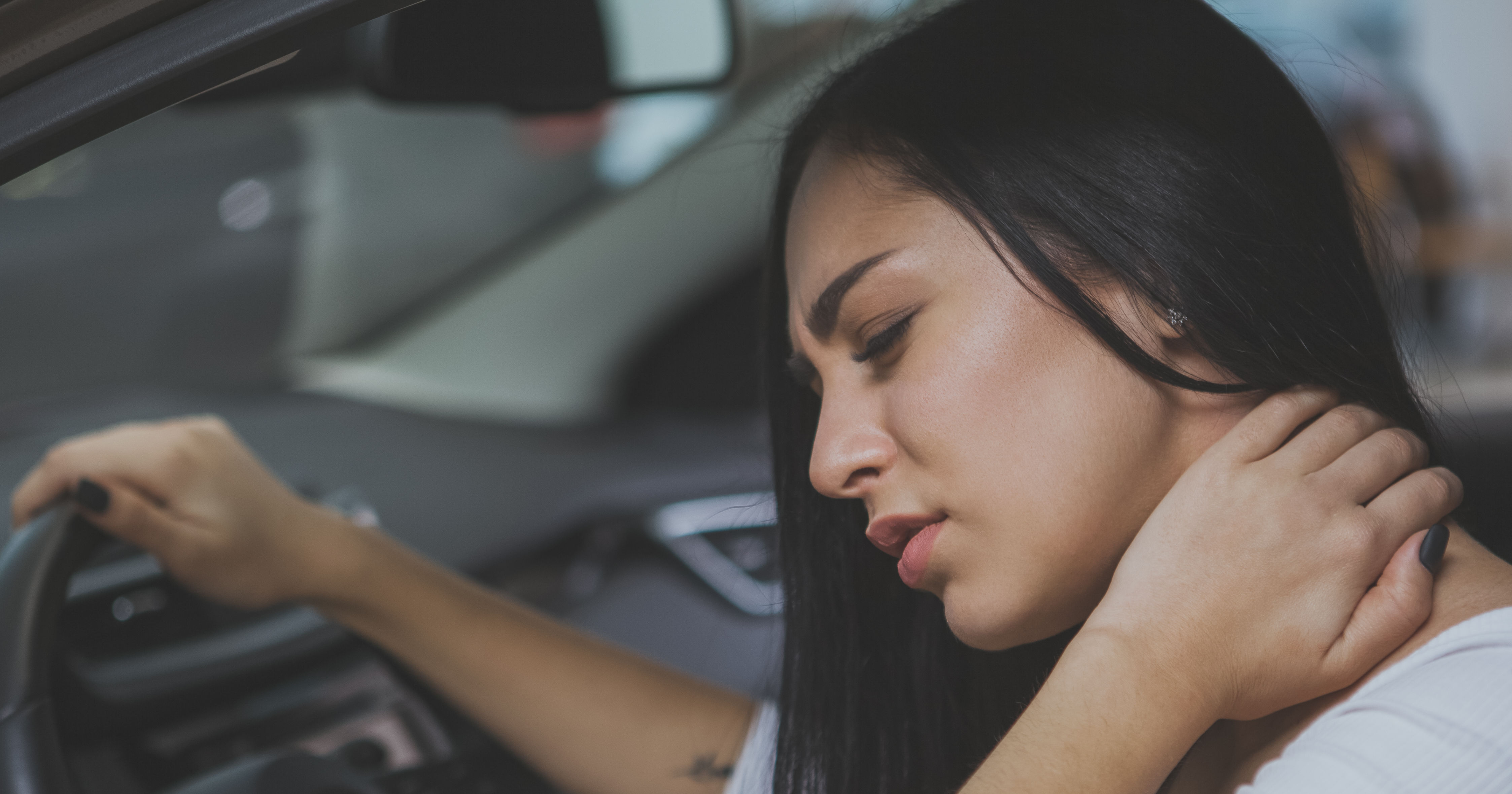 Female driver rubbing her aching neck after long d