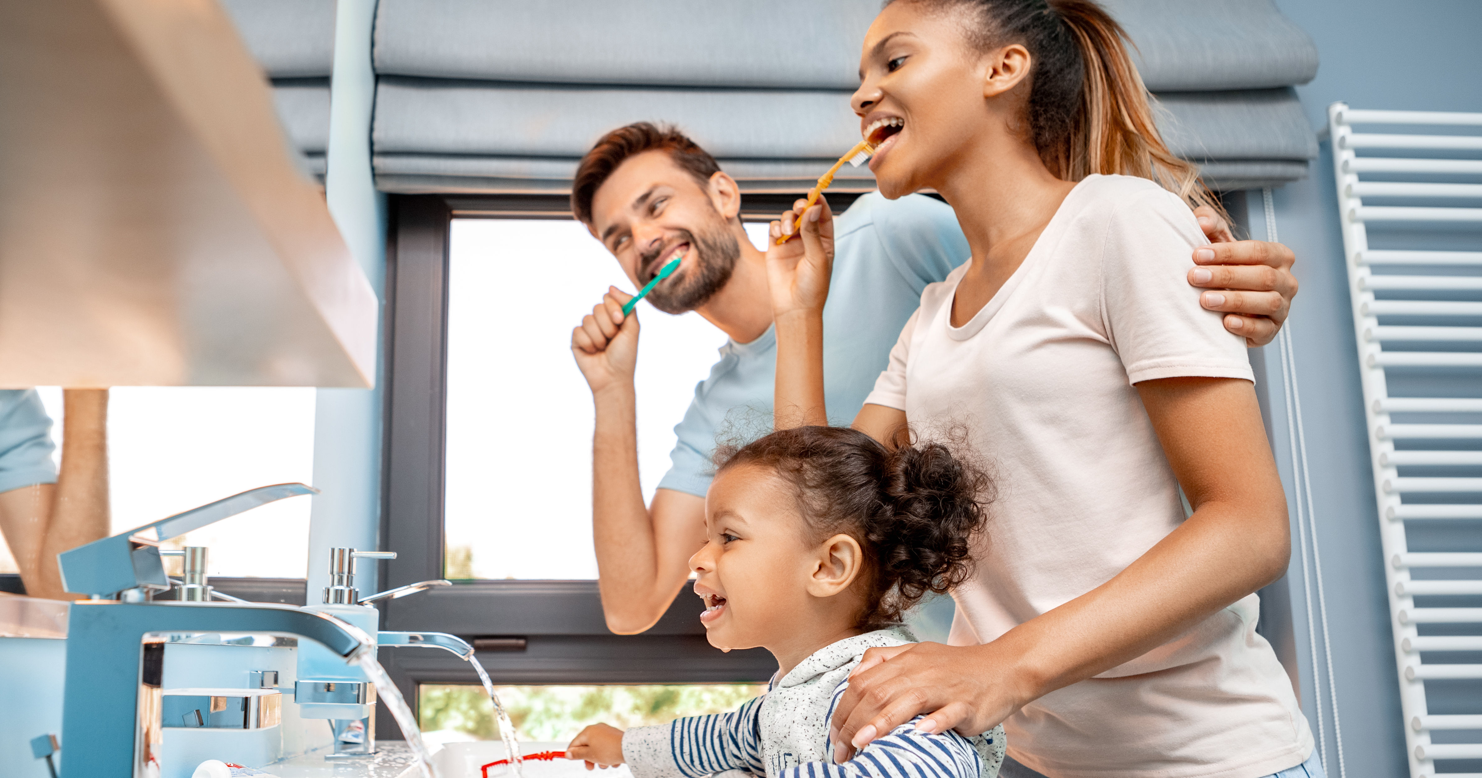 Mother, father and daughter brushing teeth in bath