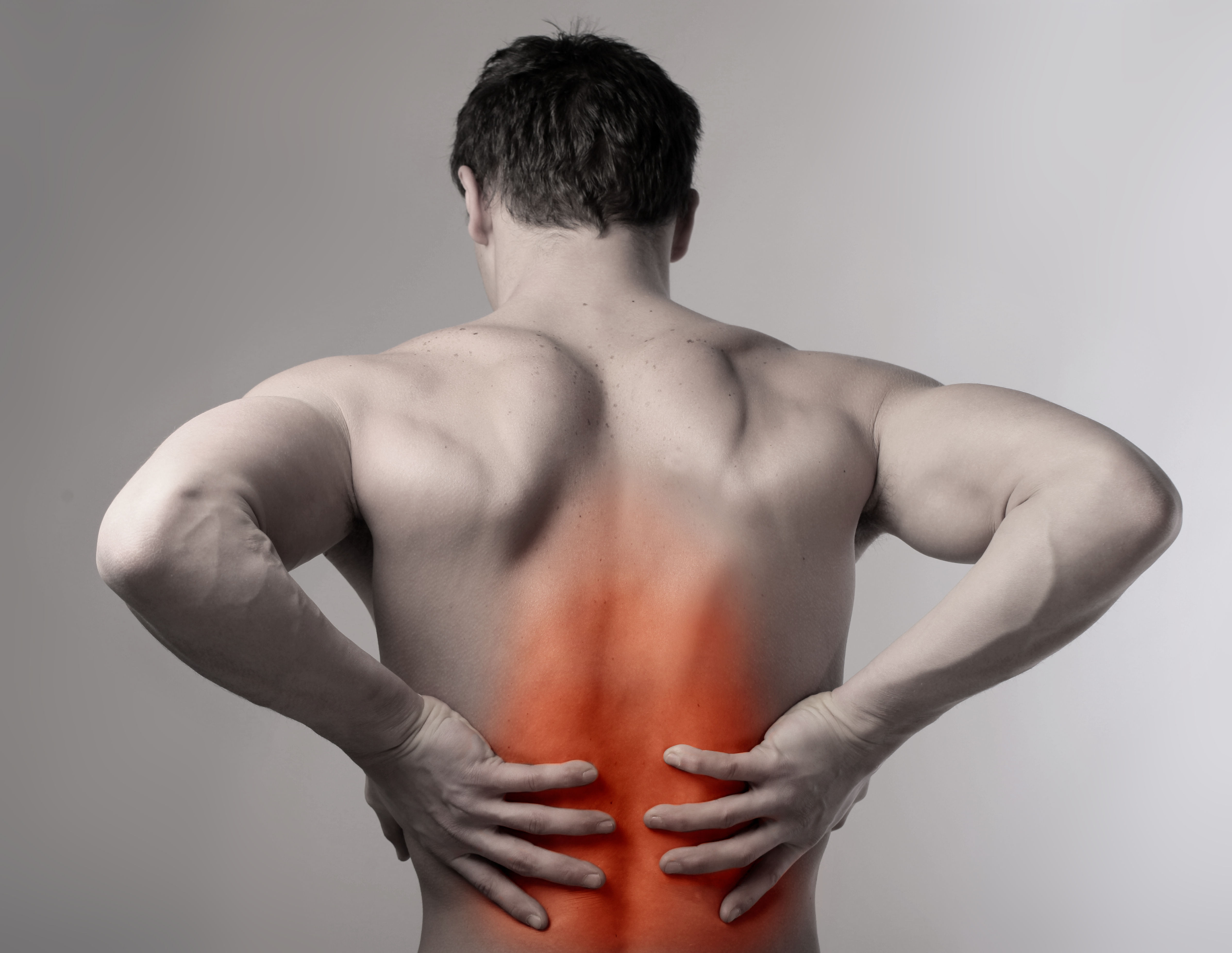 The image shows a muscular man seen from behind, holding his lower back with an orange highlight indicating pain or discomfort in that area.
