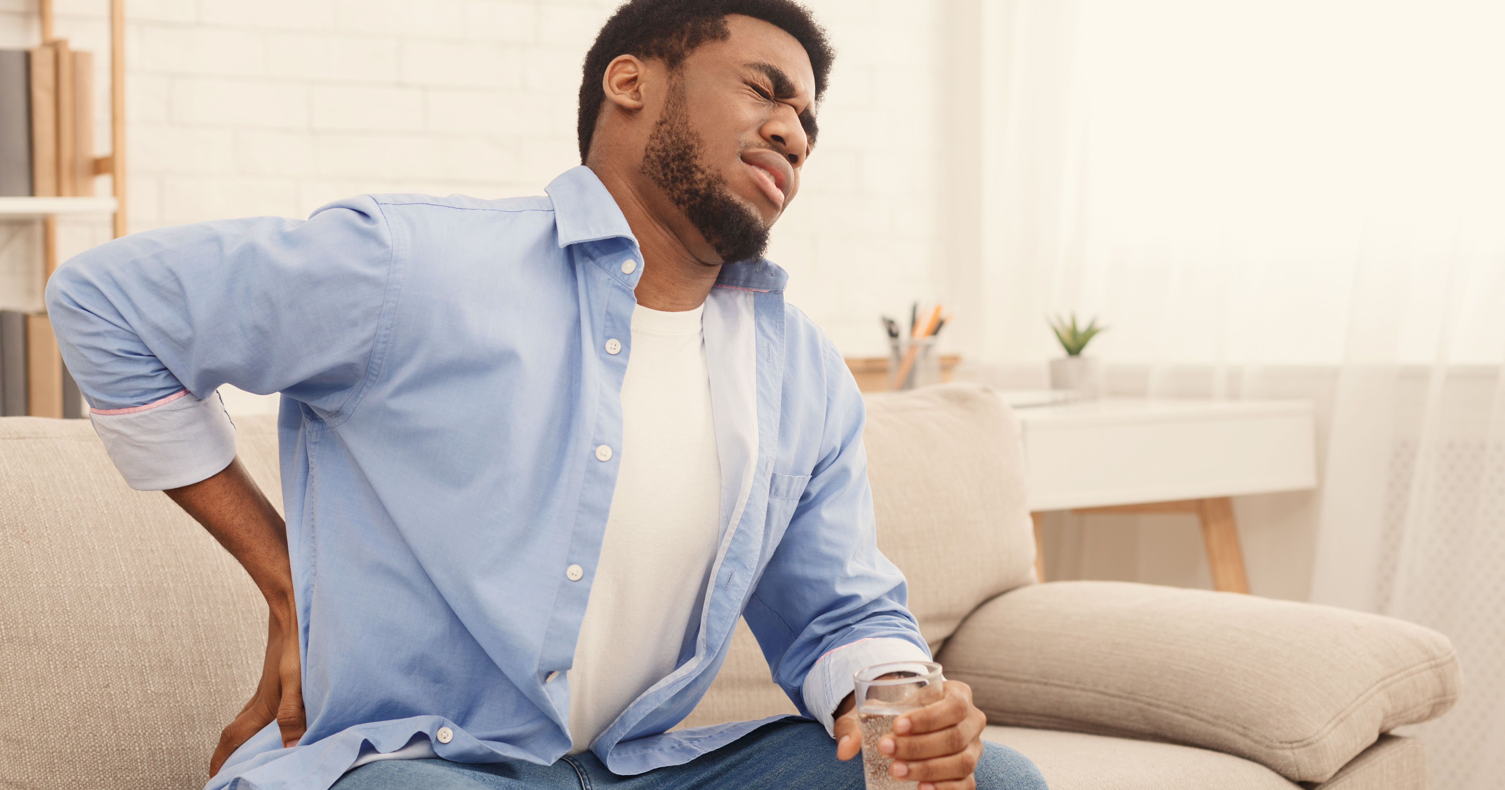 Young black man with back pain at home