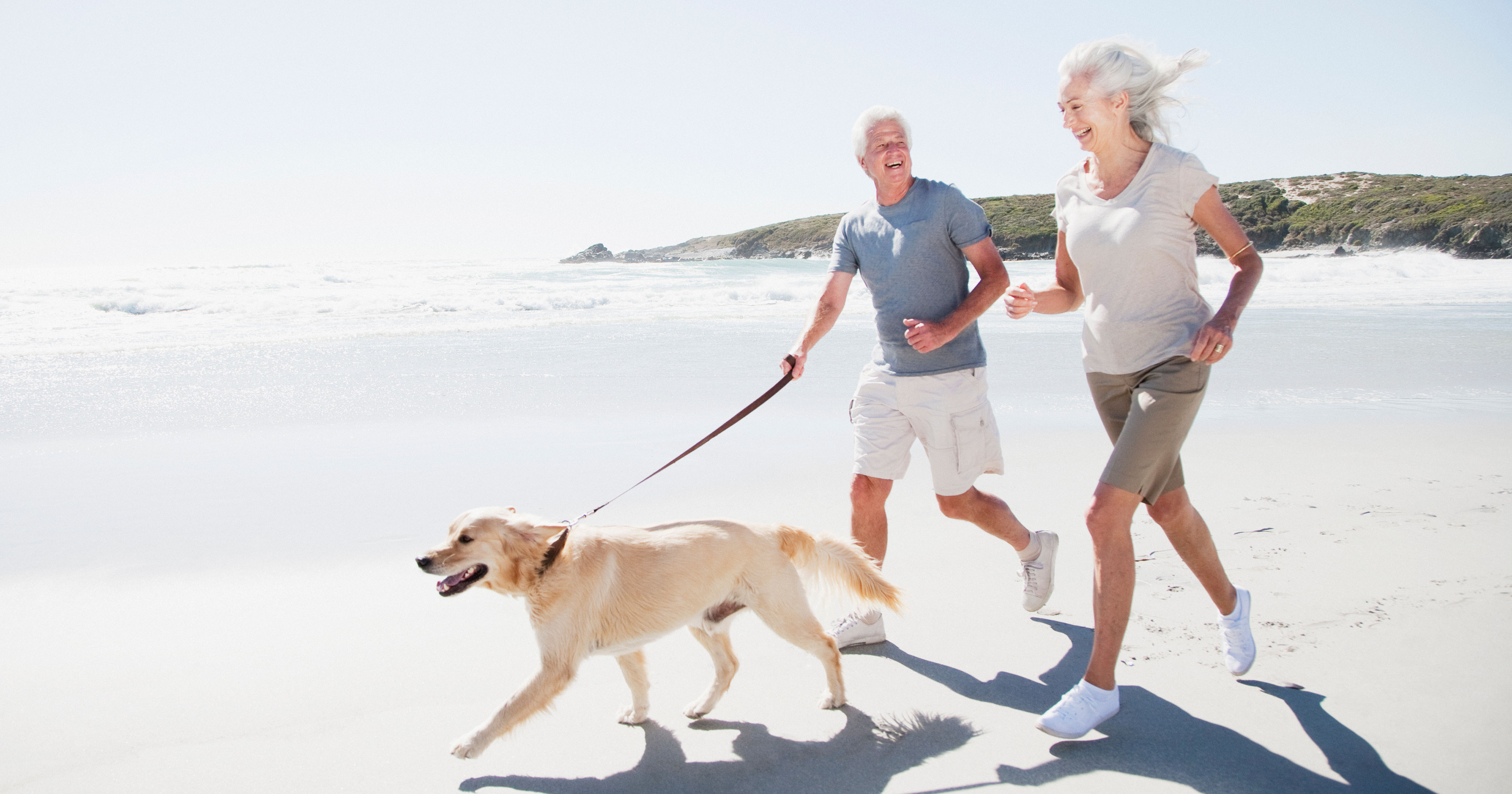 Senior couple running on beach with dog
