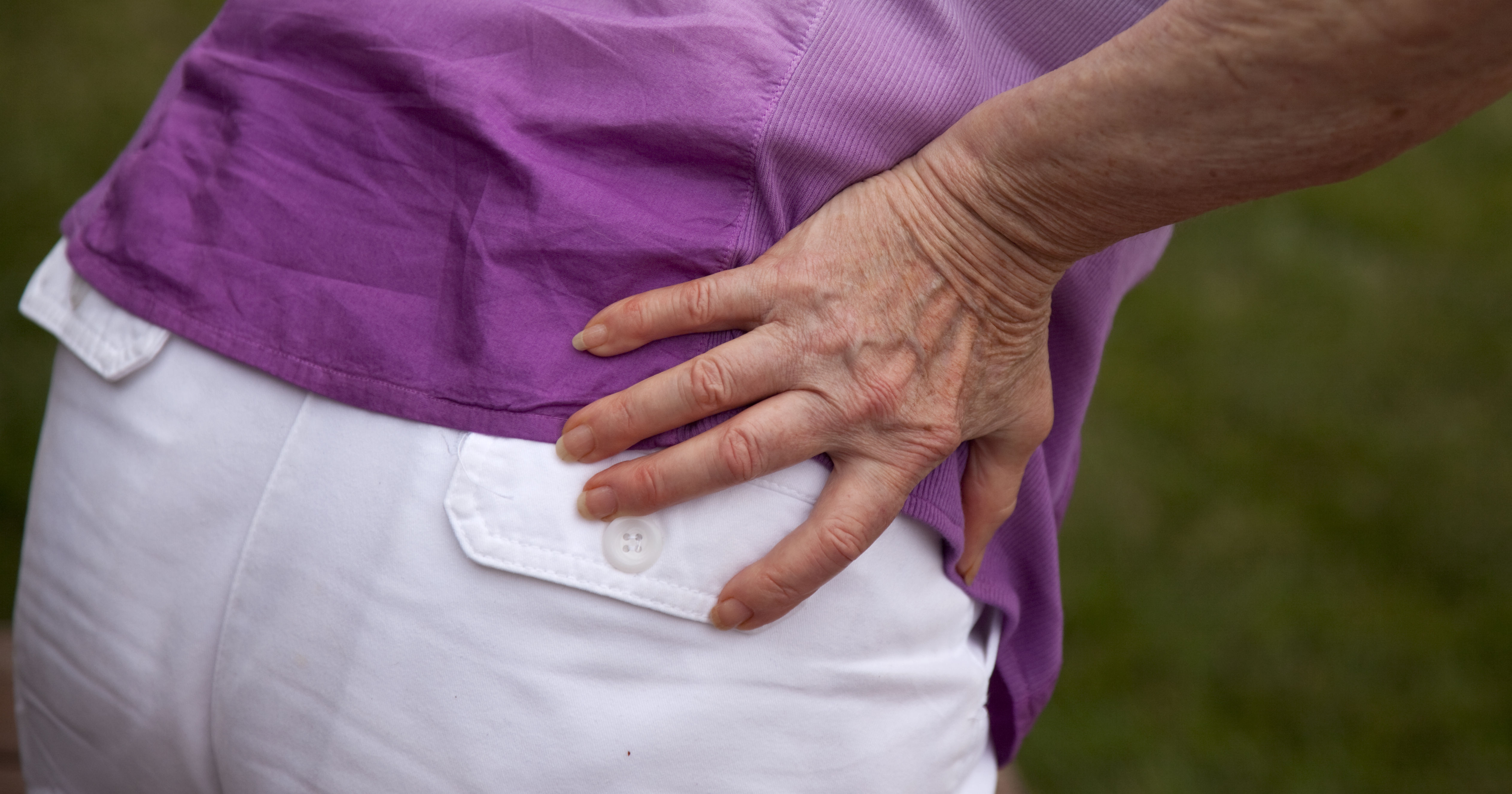 Senior woman holding hip and bending over