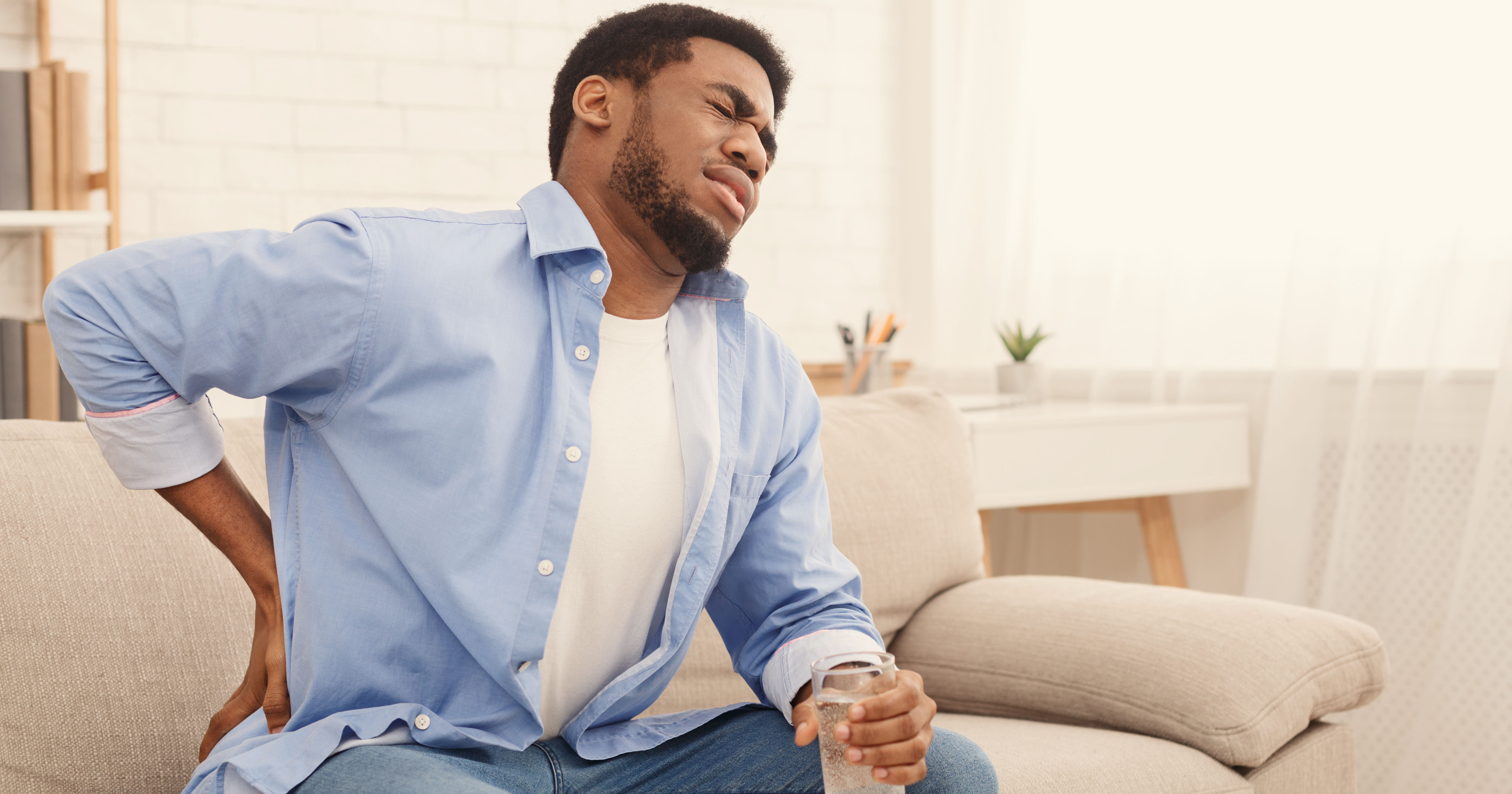 Young black man with back pain at home