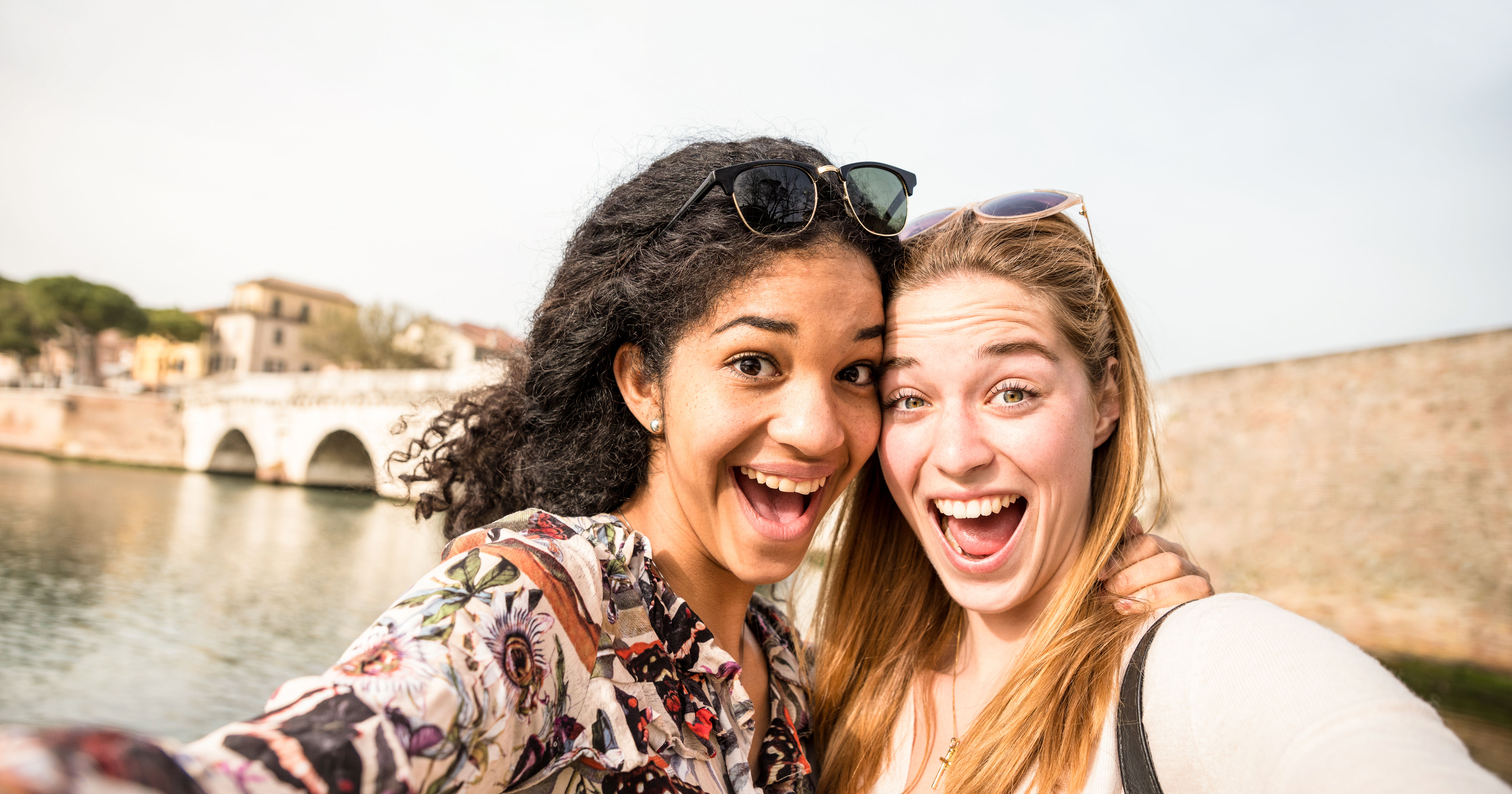 Happy multiracial girlfriends taking selfie and ha