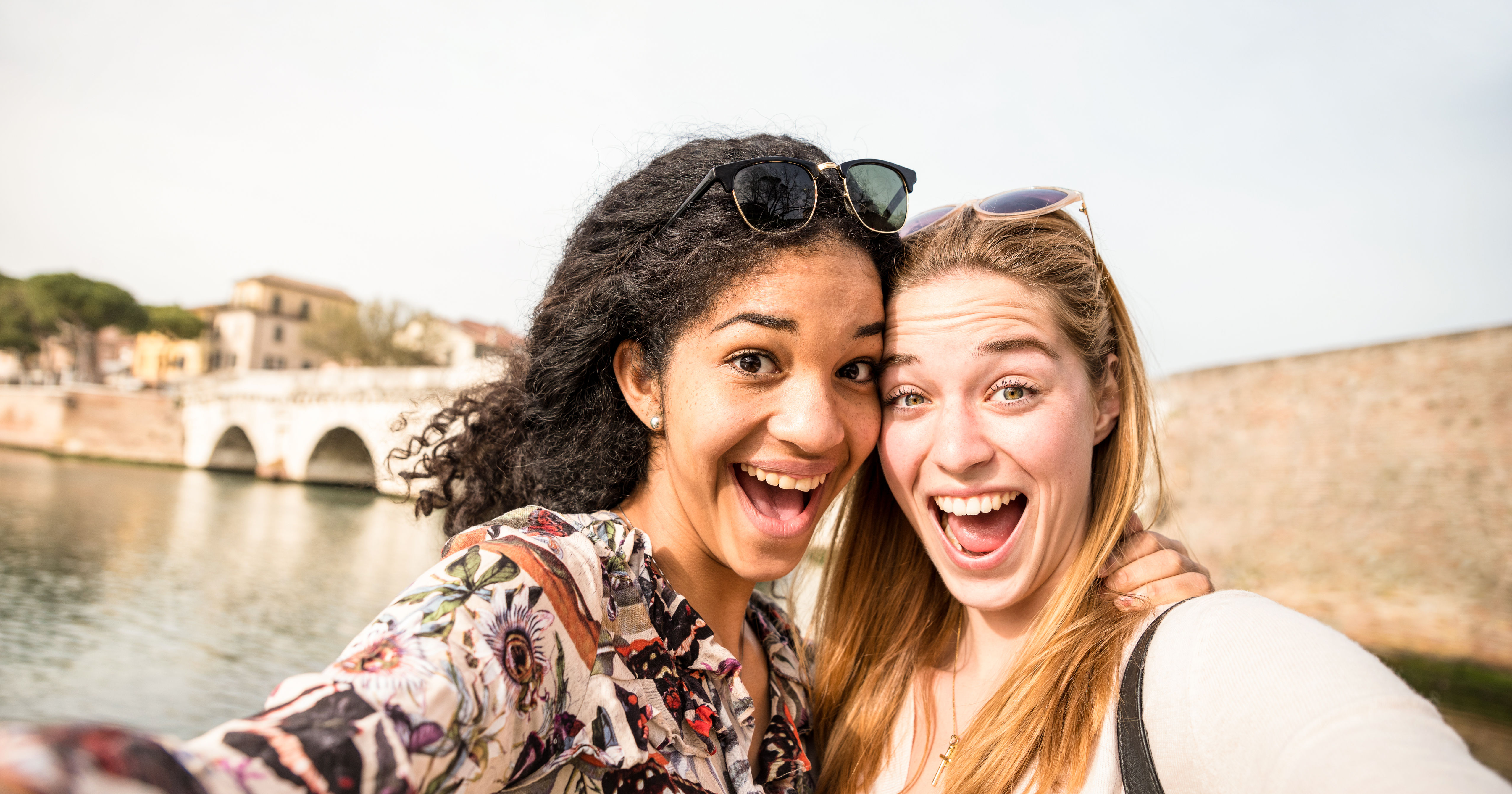 Happy multiracial girlfriends taking selfie and ha