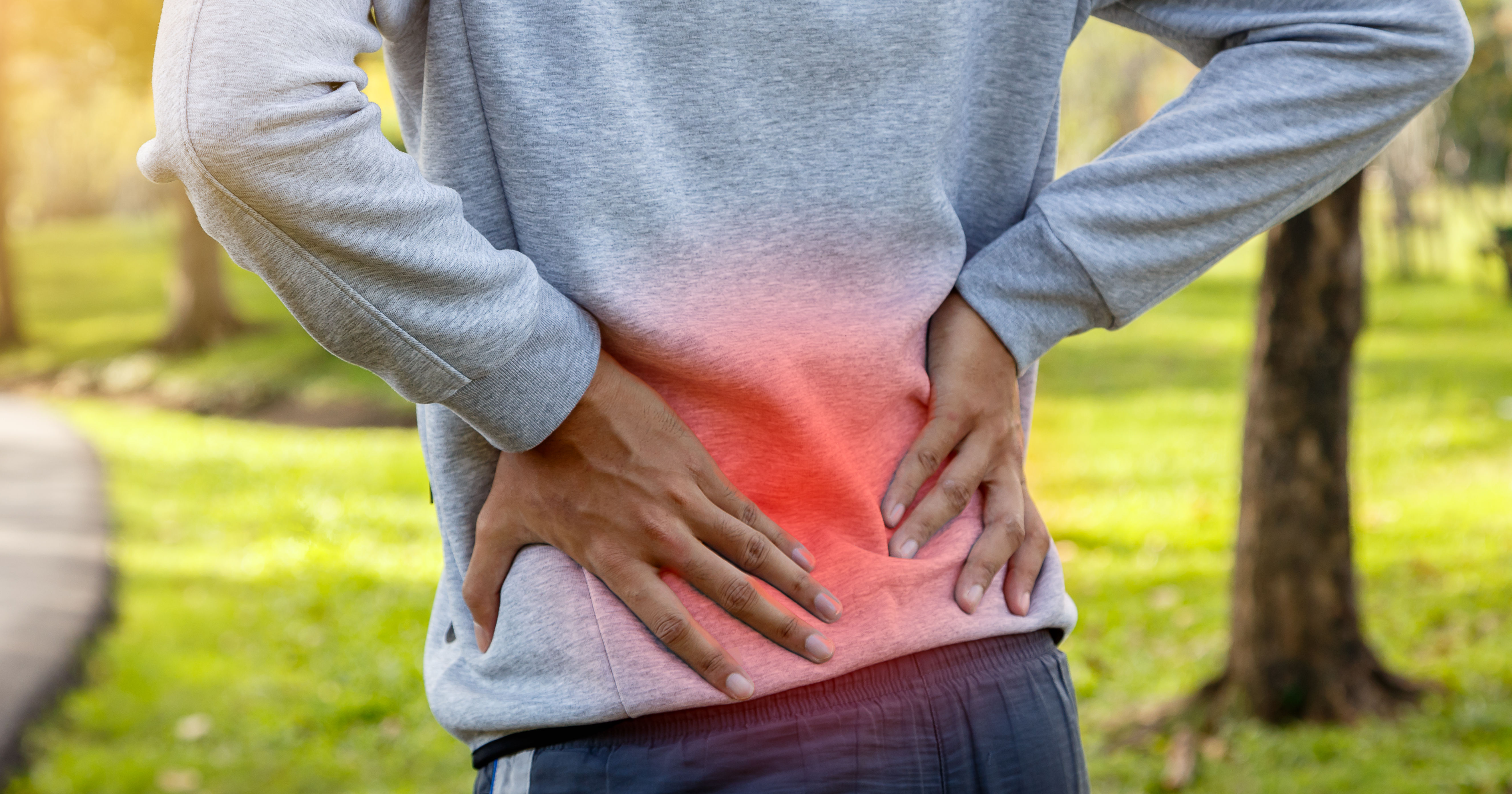 Sport man suffering from backache at park outdoors