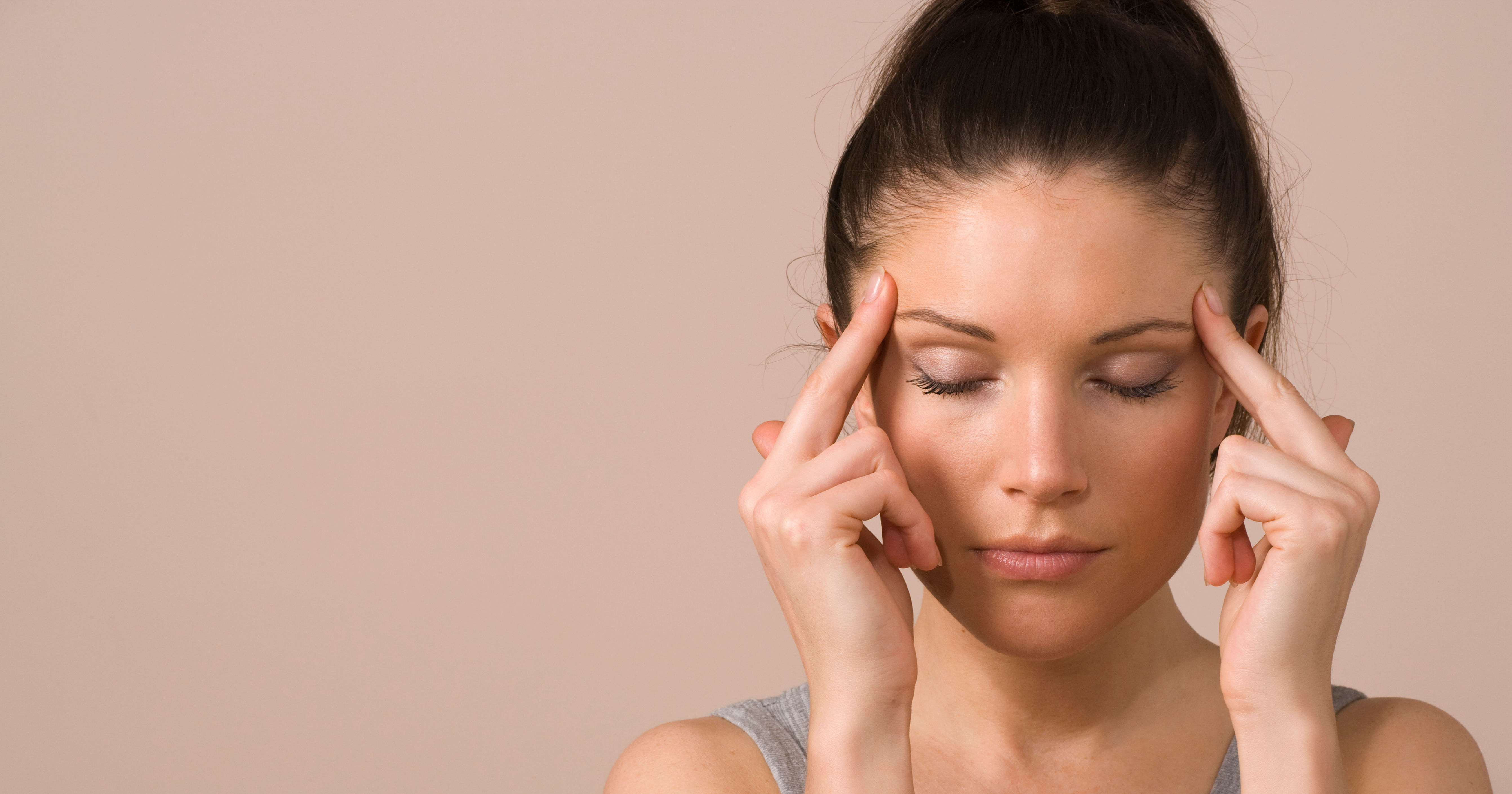 woman touches head with eyes shut