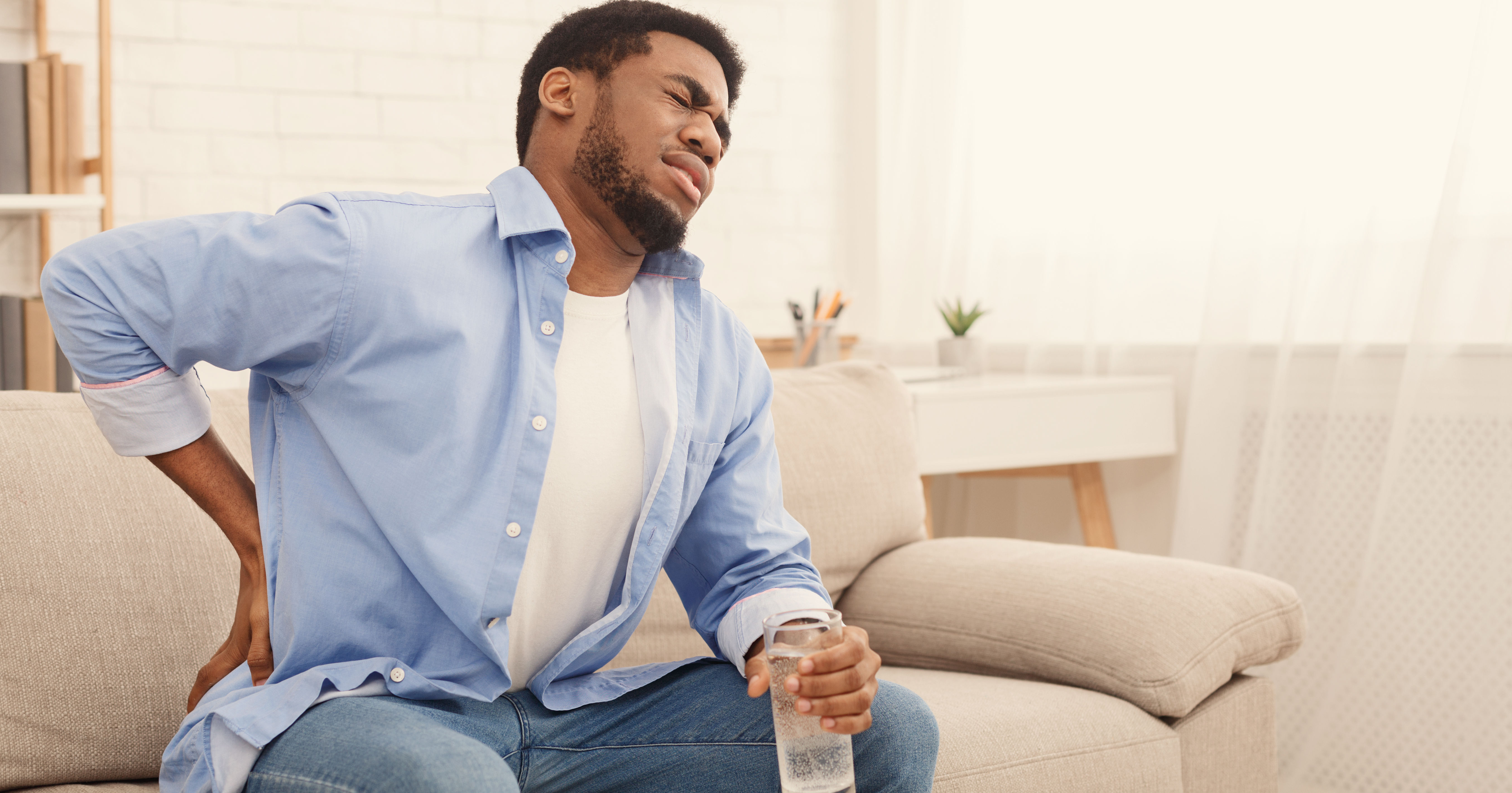 Young black man with back pain at home