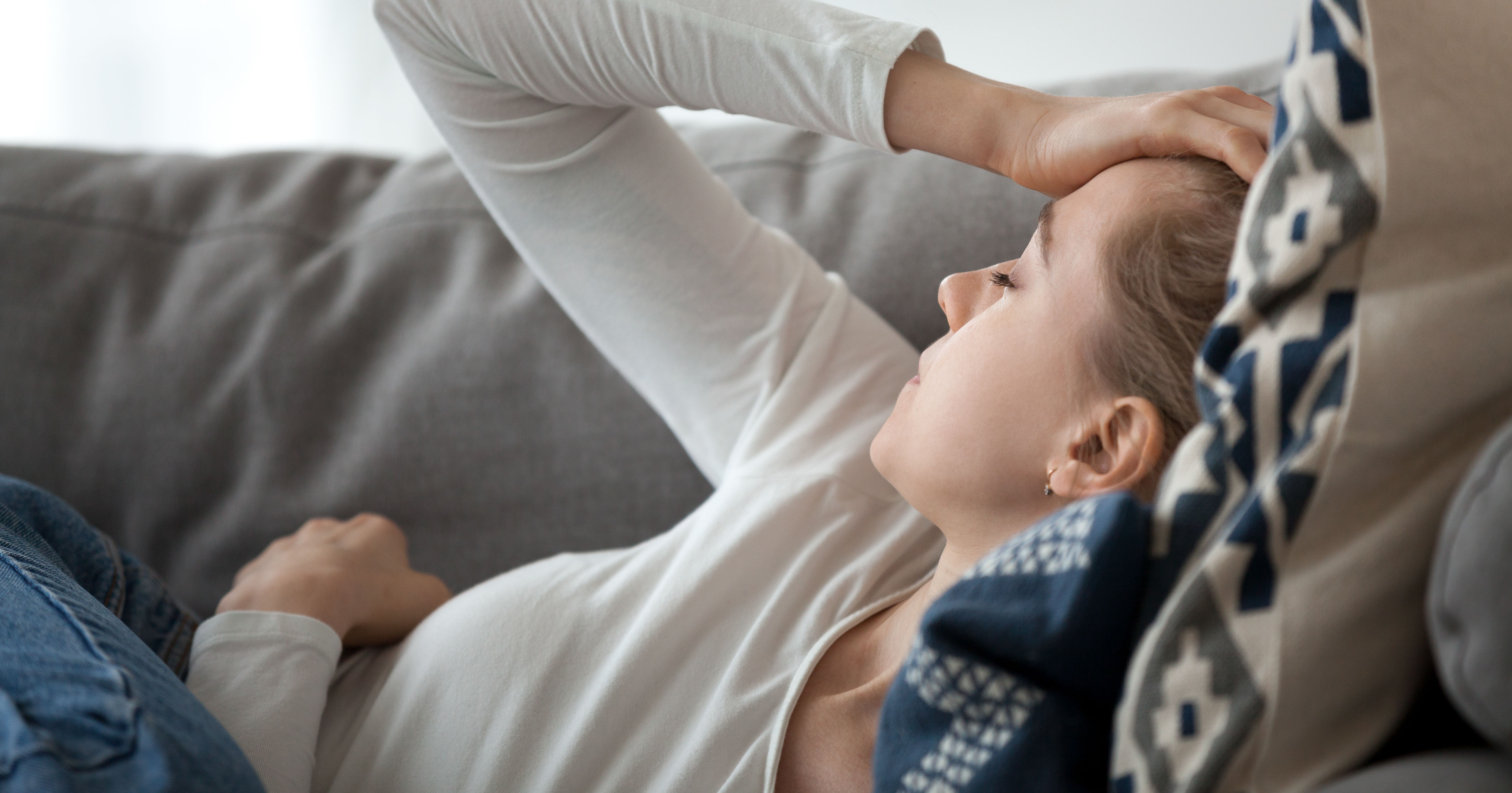 Upset depressed young woman lying on couch feeling