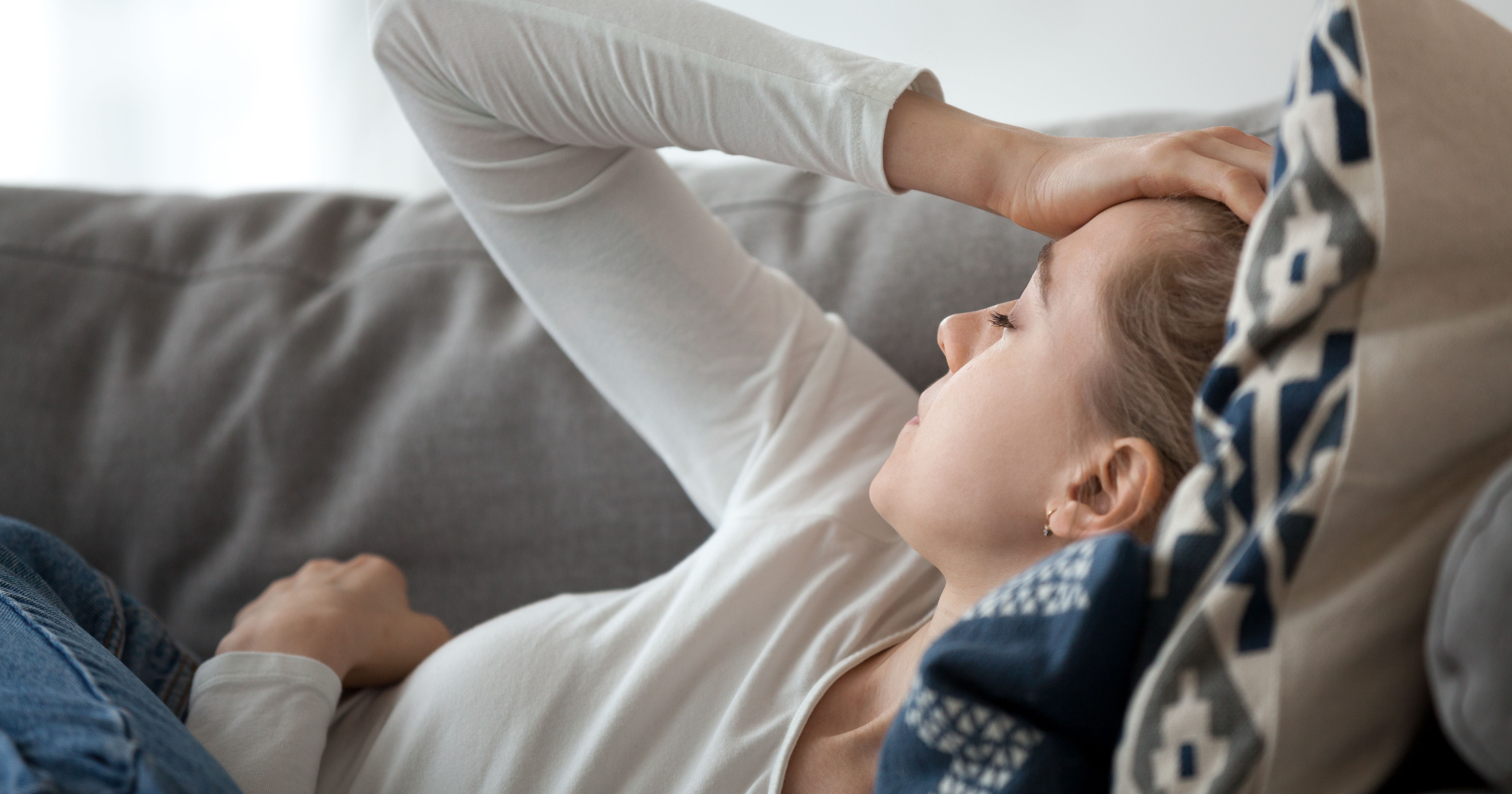 Upset depressed young woman lying on couch feeling