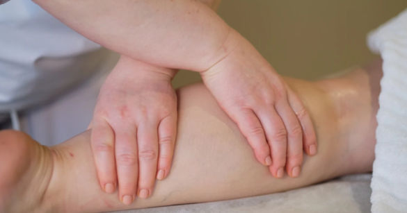 Therapist performing manual lymphatic drainage massage on a patient’s lower leg to help reduce lymphoedema fluid buildup.