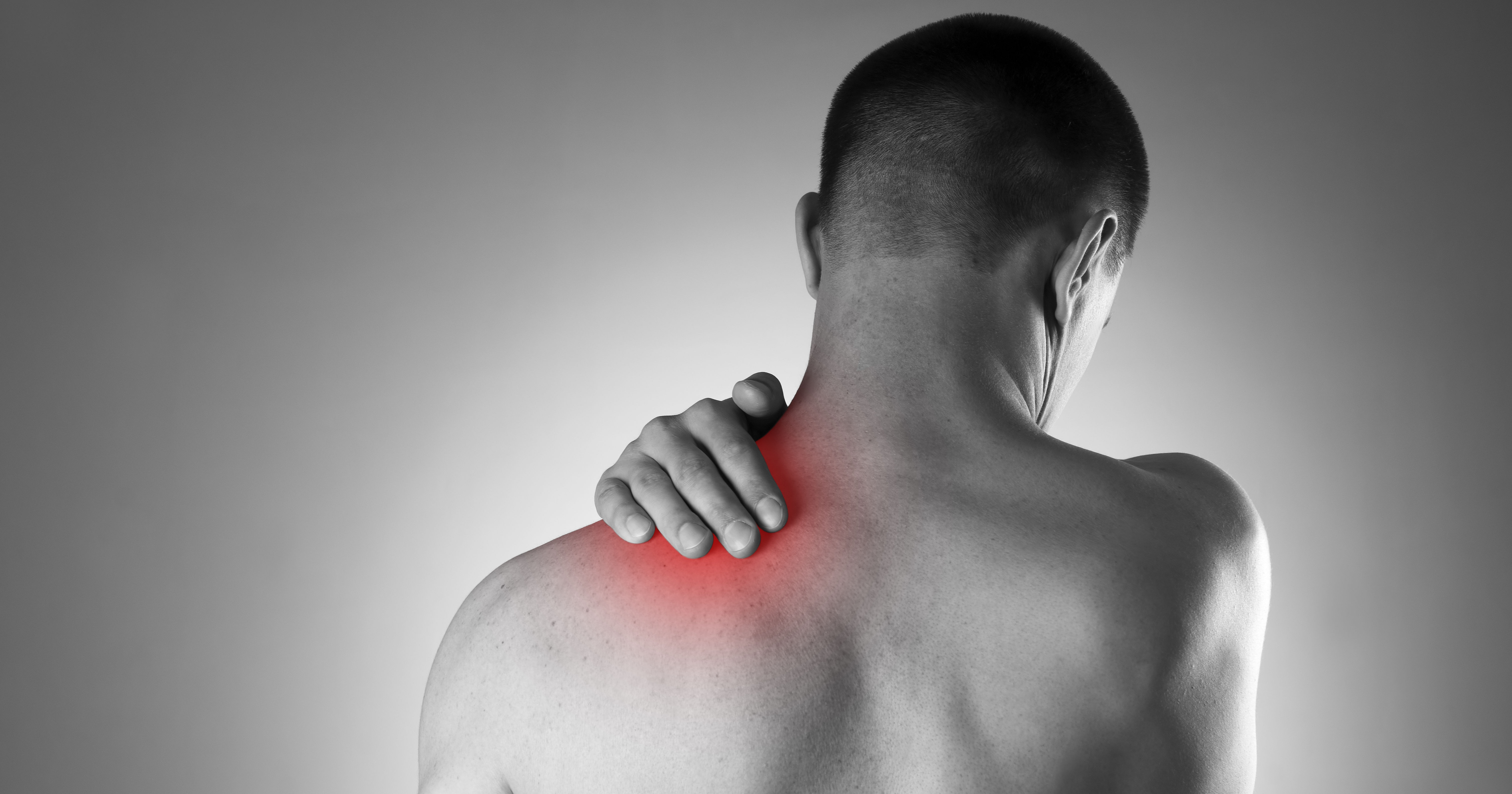 The image shows a person with their back turned, holding their shoulder, indicating discomfort or pain in the shoulder area.