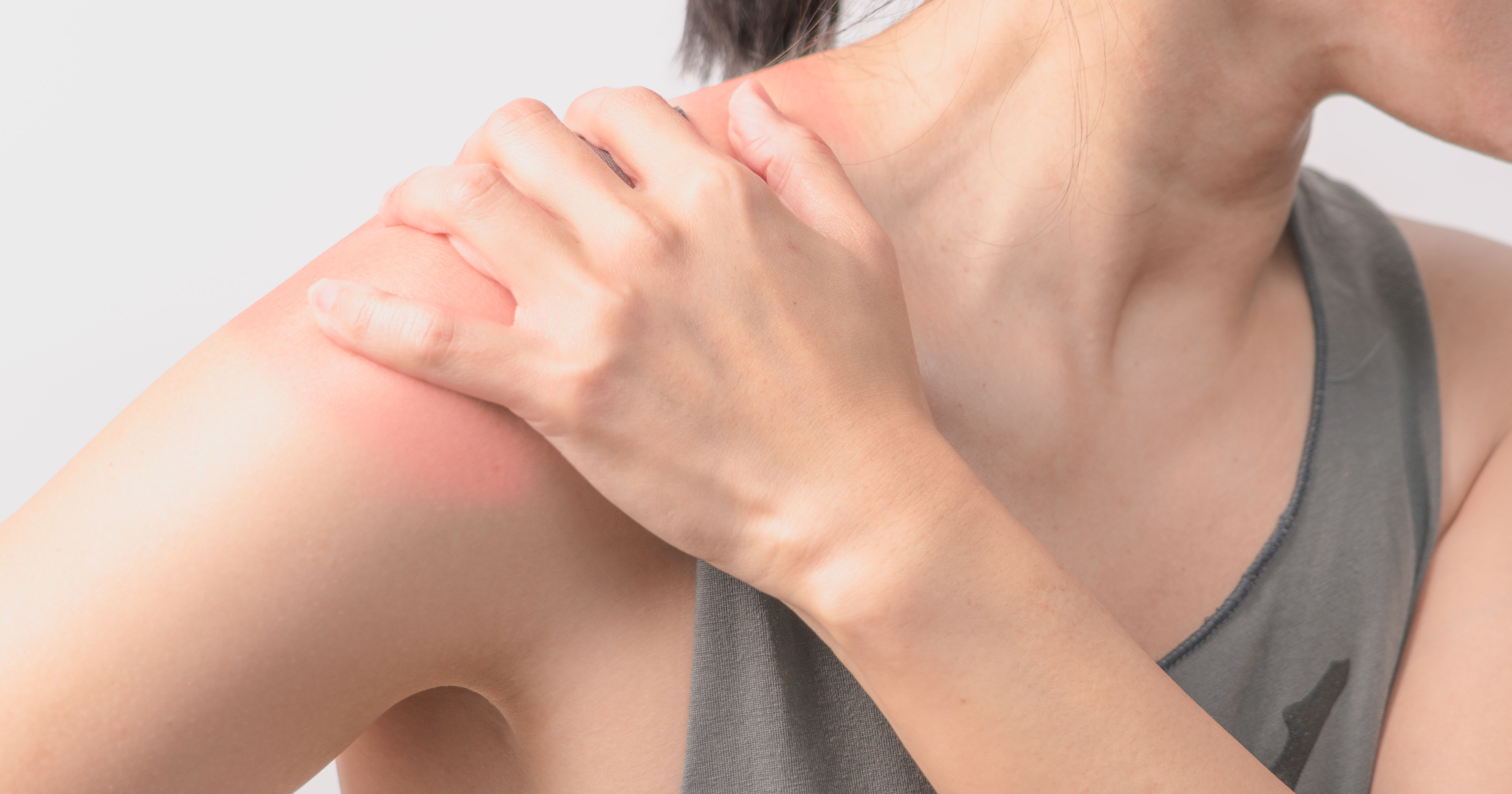 The image shows a person holding their shoulder, which appears to have a reddish area, indicating discomfort or irritation.