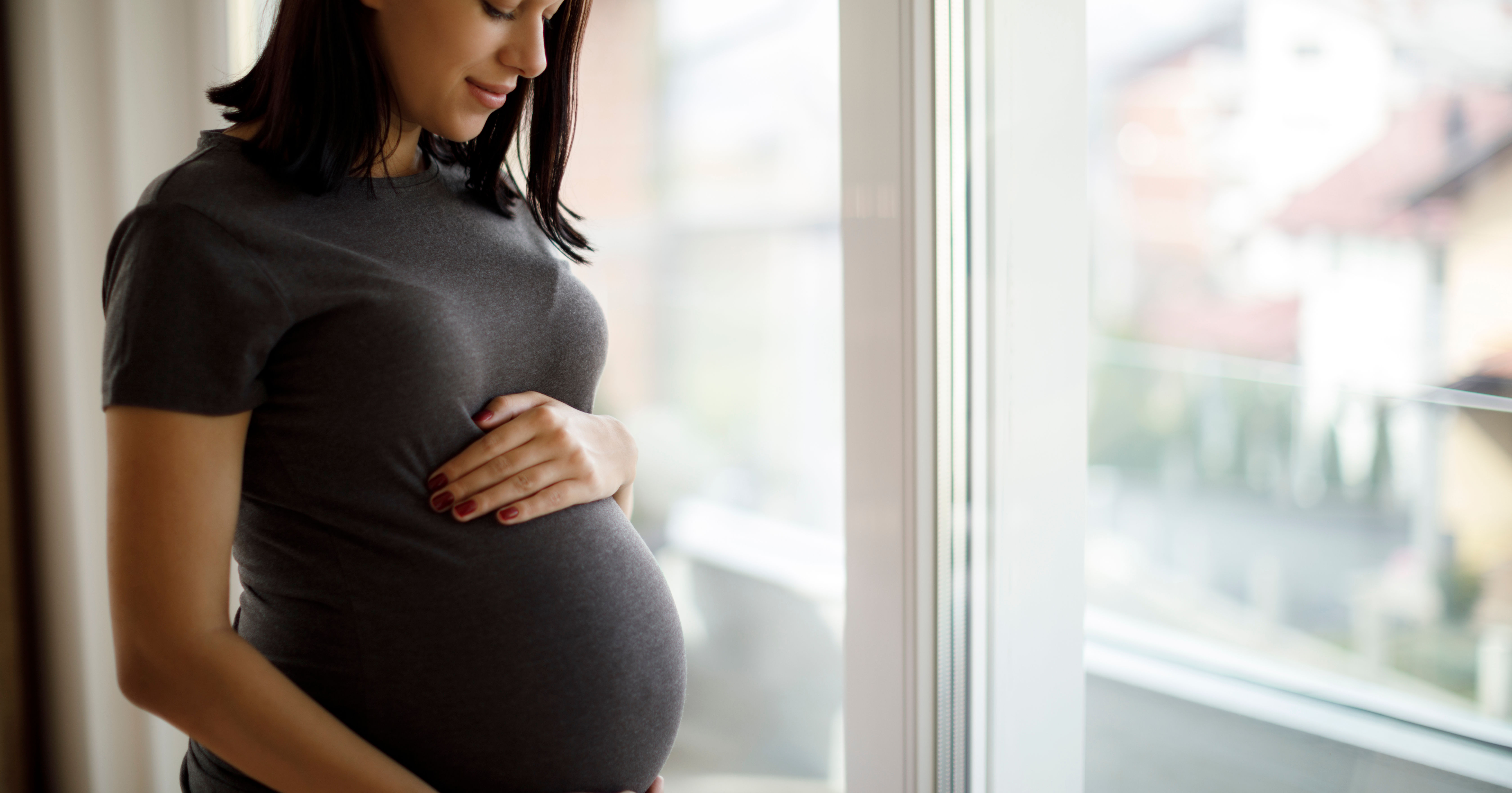 Portrait of young happy pregnant woman standing by
