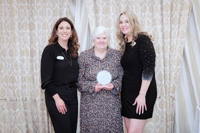 woman holding an award standing in between two women