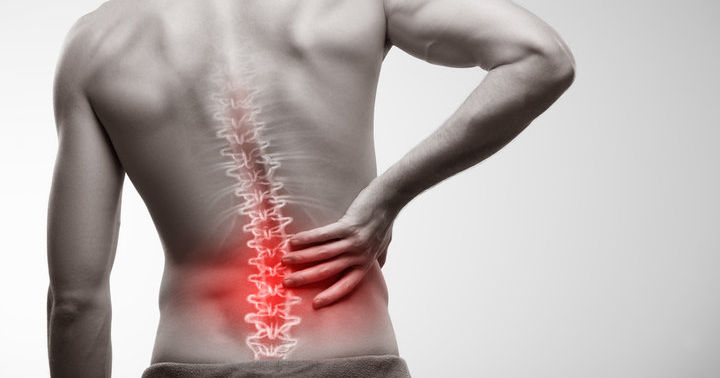 Man with highlighted lower spine in red, holding his lower back to indicate pain or discomfort.