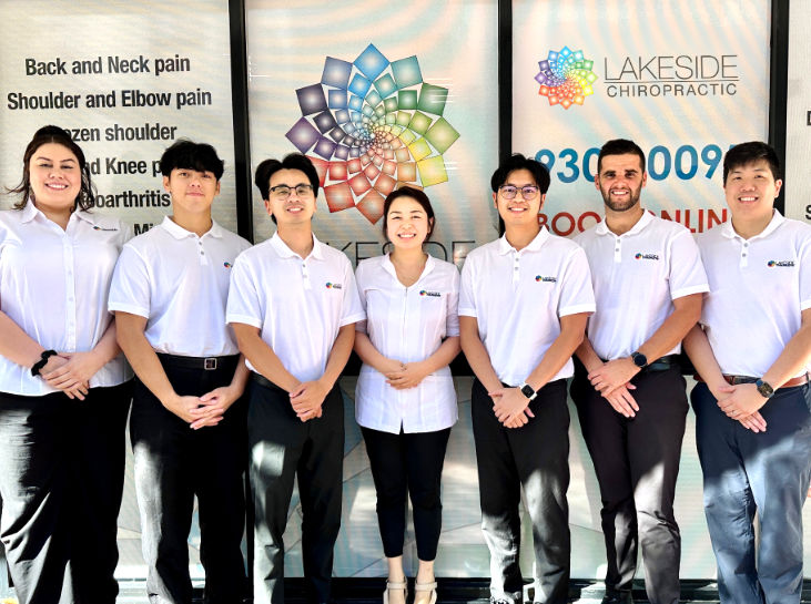 Team of chiropractors and staff standing outside Lakeside Chiropractic clinic in Perth, smiling in white uniforms