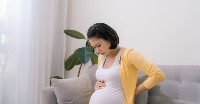 pregnant woman holds back in pain