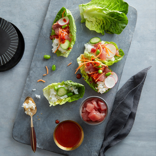 slate tray with fresh raw lettuce leaves filled with ahi tuna poke and sushi rice